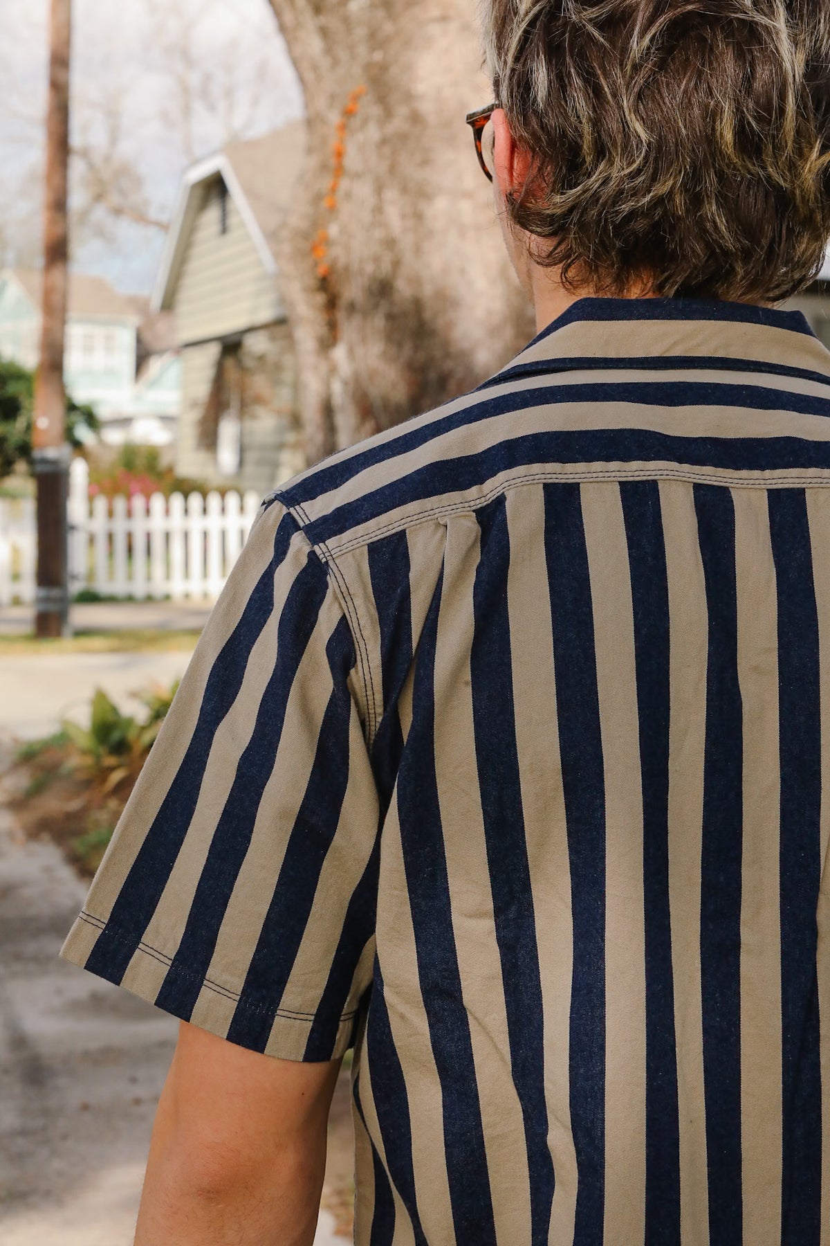 Person wearing a navy and beige striped shirt with a blurred background