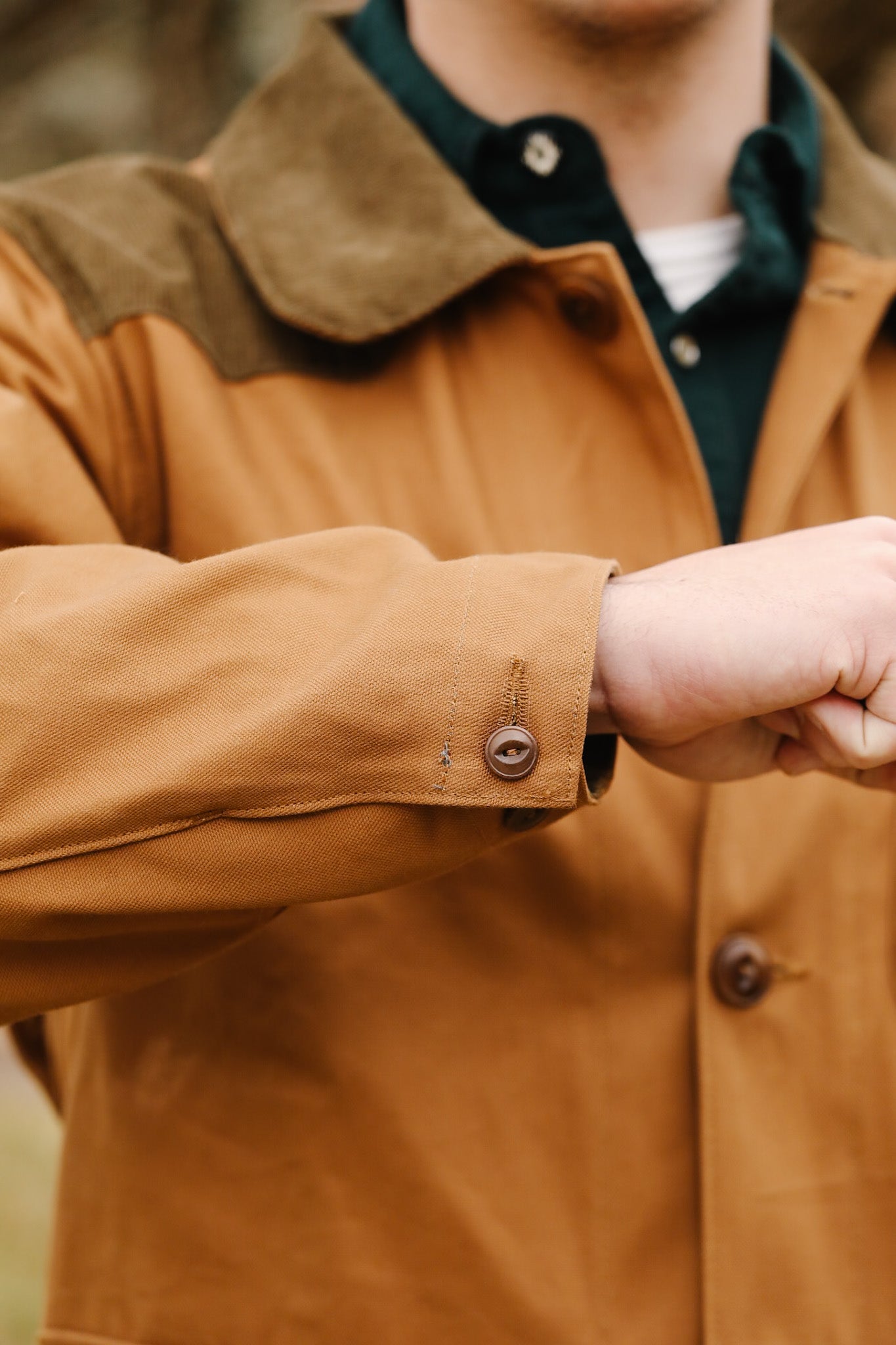 Close-up of a person wearing a brown jacket with a green collar.