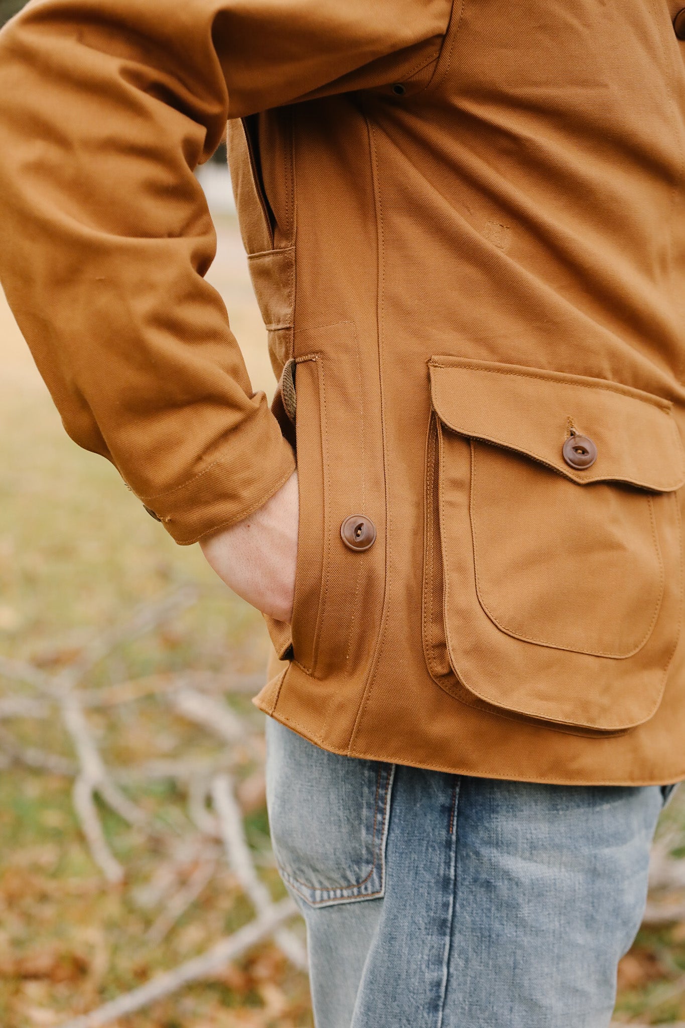 Person wearing a brown jacket with a pocket in an outdoor setting