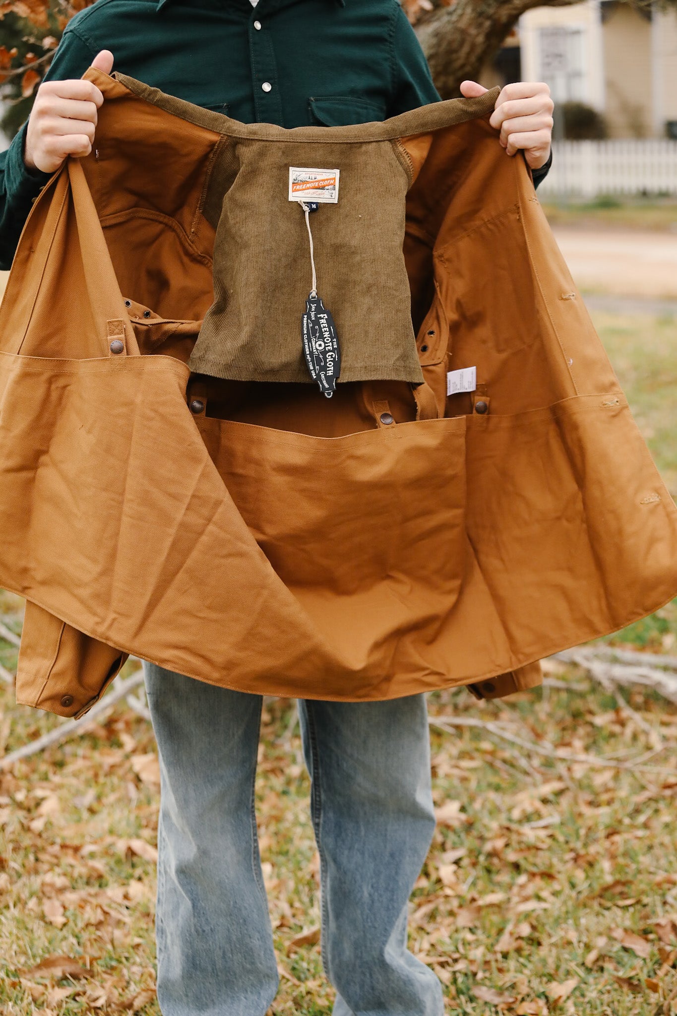 Person holding a large brown bag outdoors with a visible brand label.