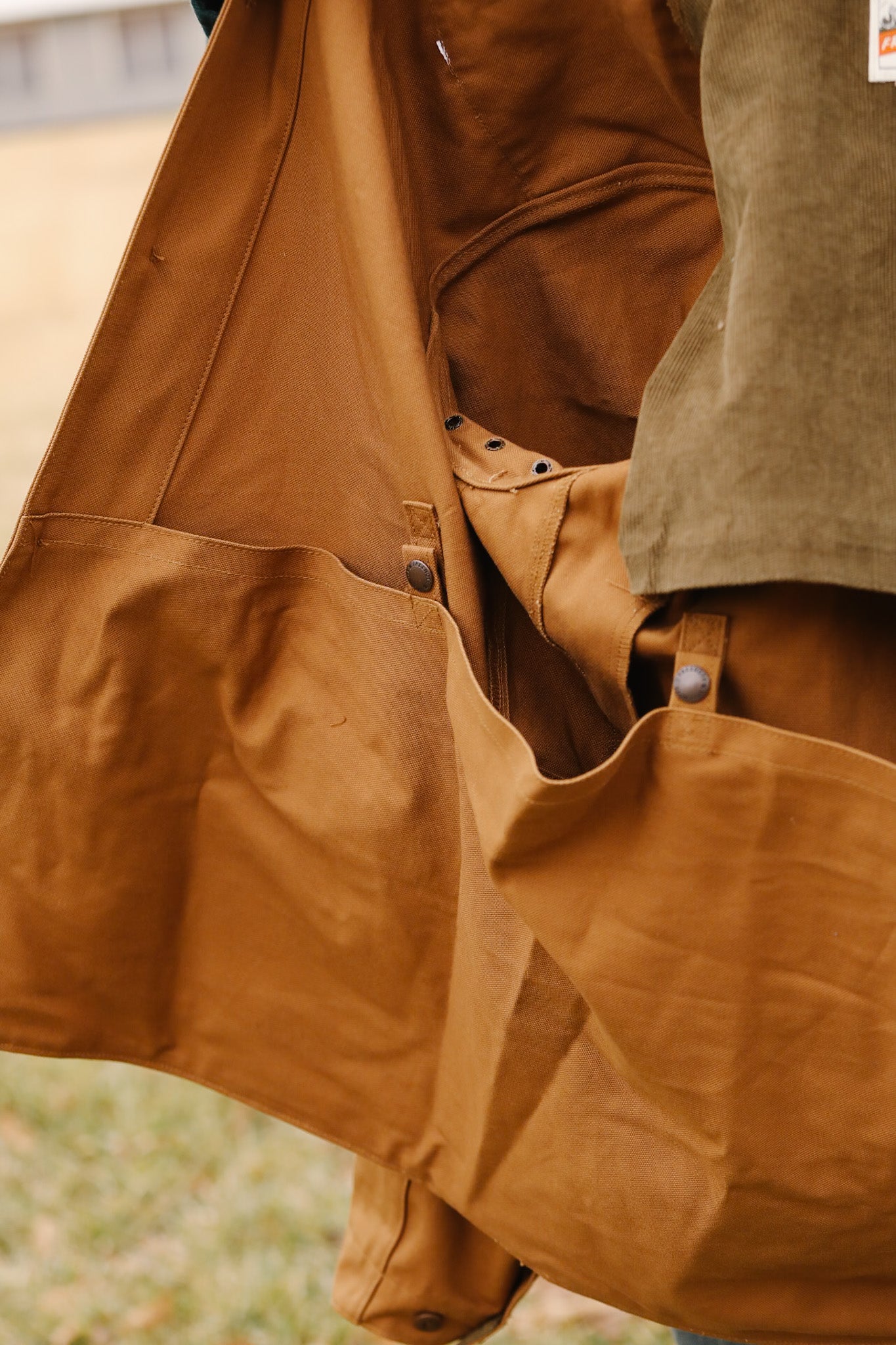 Close-up of a brown coat with visible buttons and a pocket.