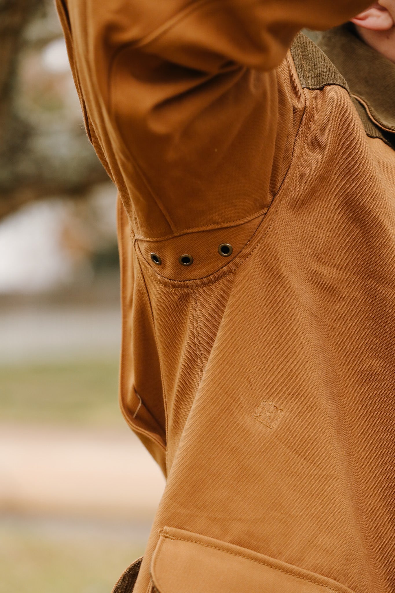 Close-up of a brown jacket with a blurred outdoor background