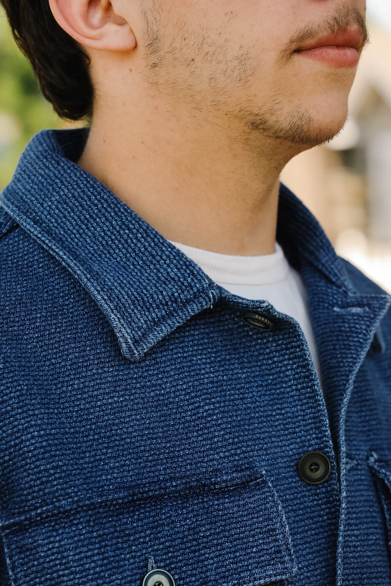 Close-up of a person wearing a blue textured jacket with a blurred background