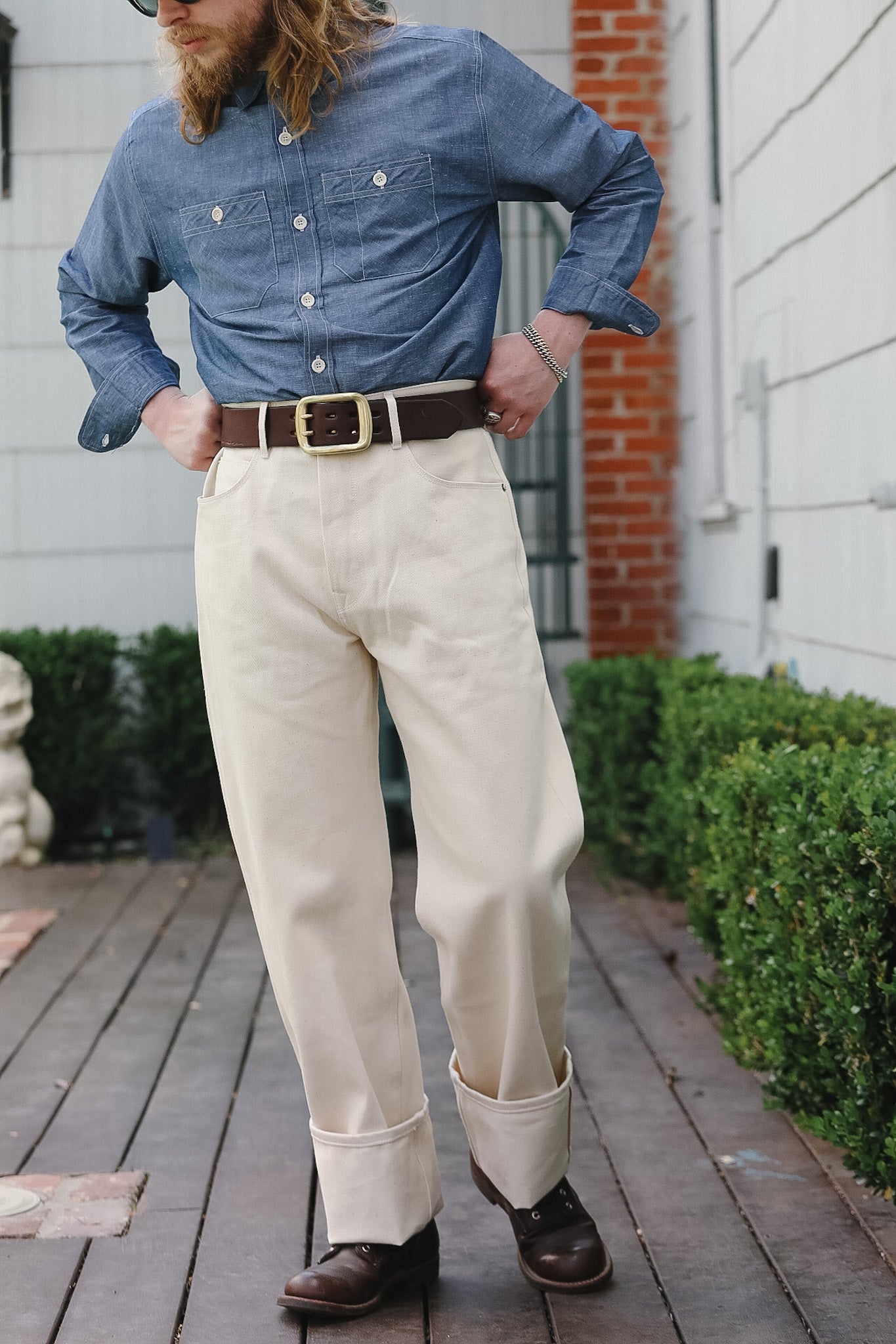 Person wearing a blue shirt, beige pants, and brown shoes on a wooden deck.