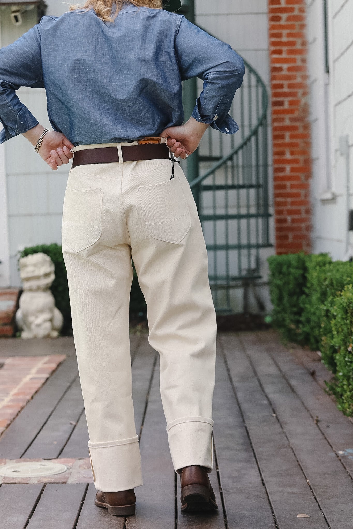 Person wearing a blue shirt, beige pants, and brown shoes on a wooden deck.