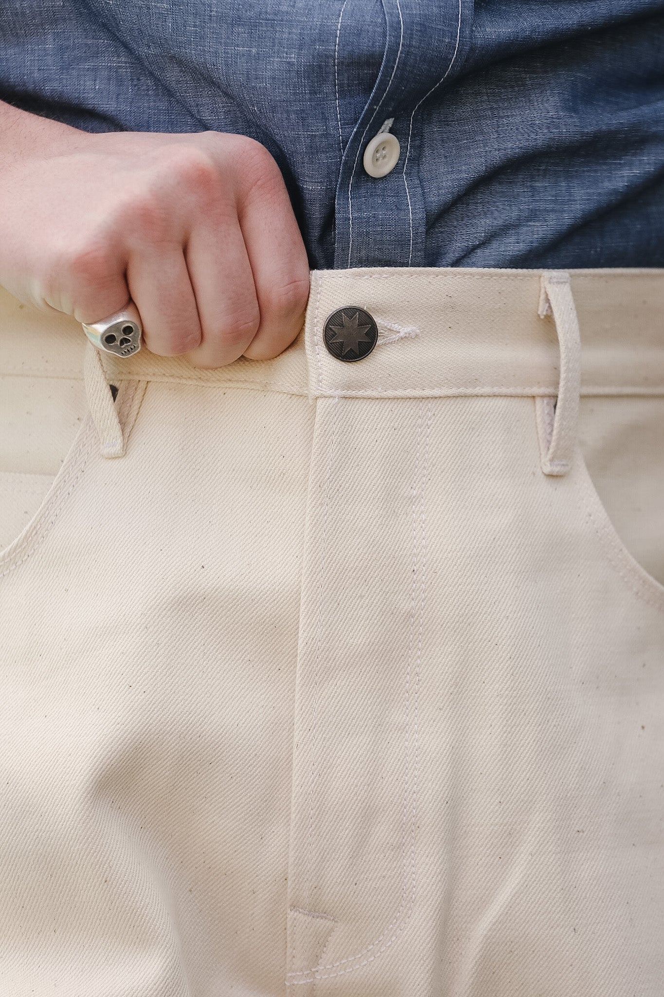 Close-up of beige pants with a person wearing a blue shirt.