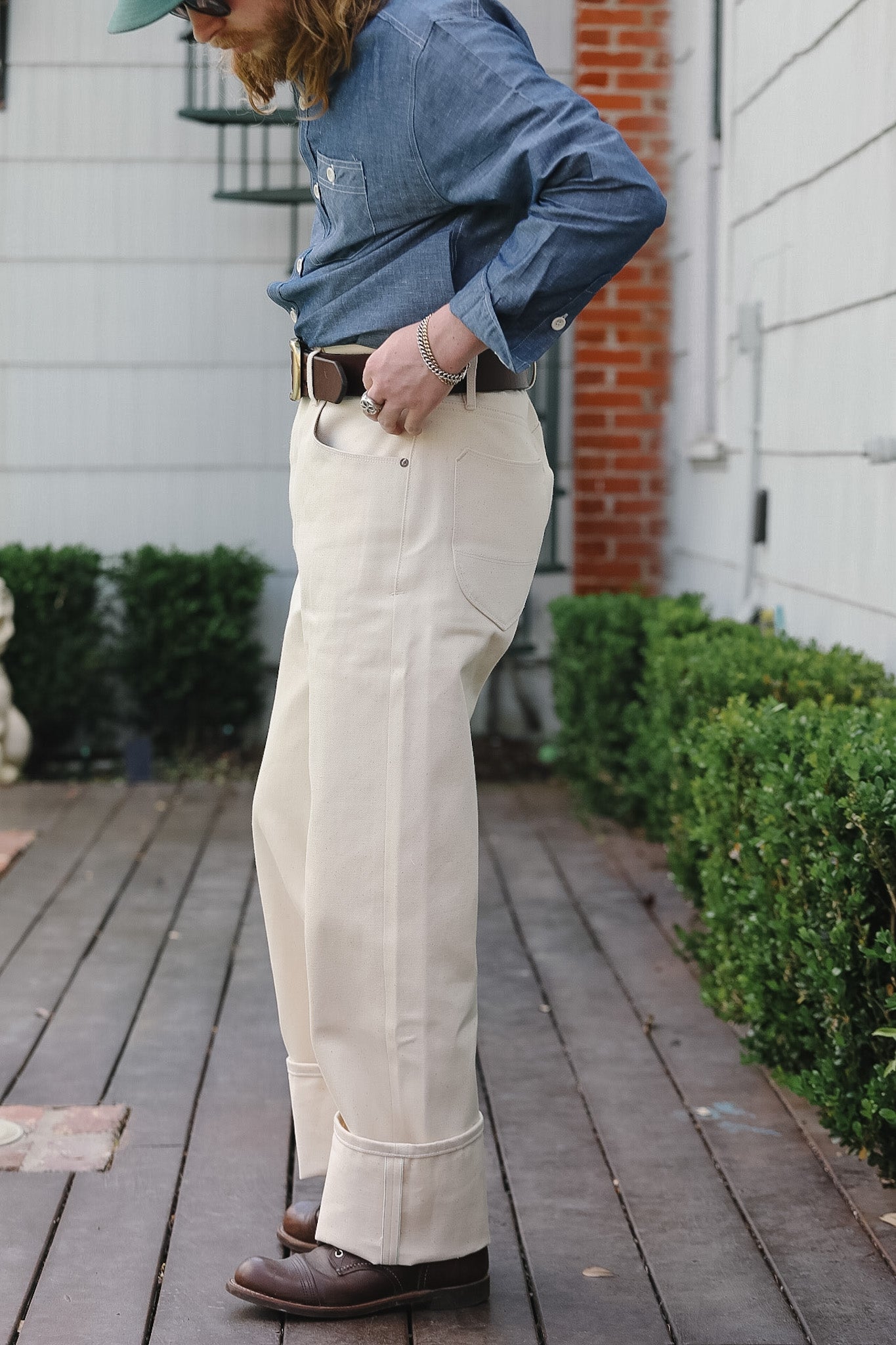 Person wearing a denim jacket and beige pants on a wooden deck.