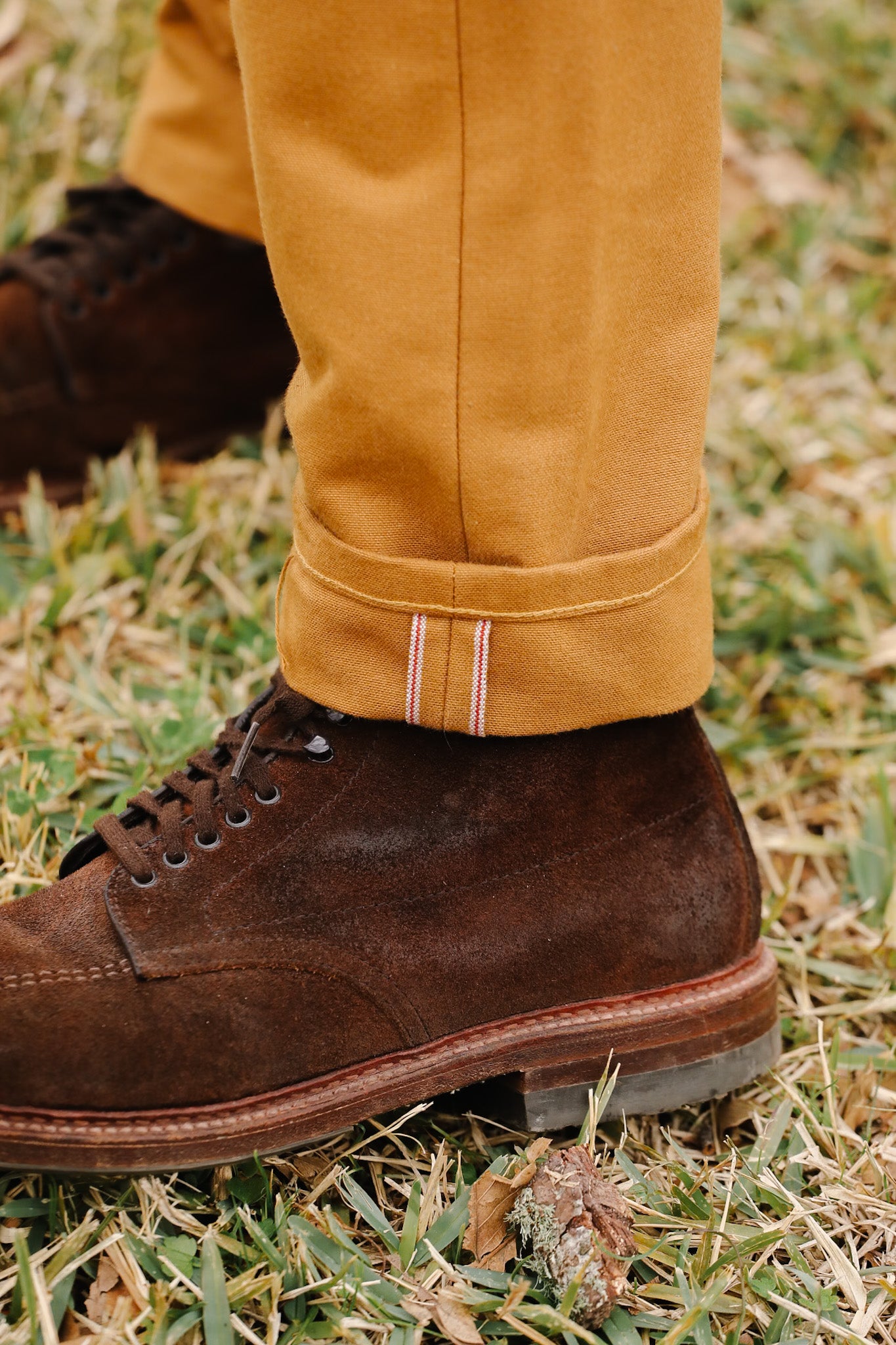 Brown leather boot and yellow pants on grass