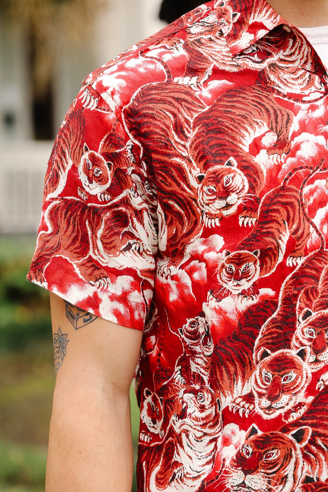 Red shirt with tiger pattern worn by a person, blurred background
