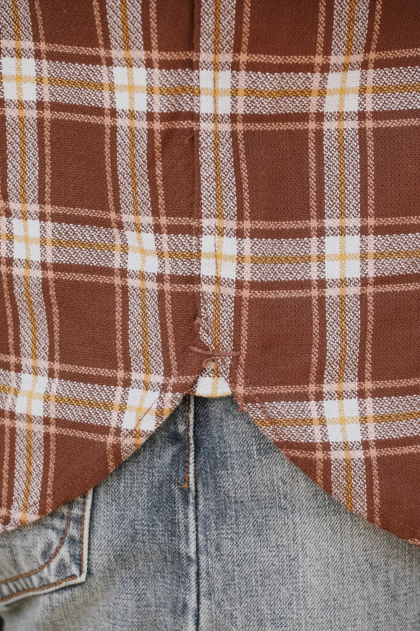 Close-up of a plaid fabric with brown, beige, and white colors, transitioning to denim fabric.