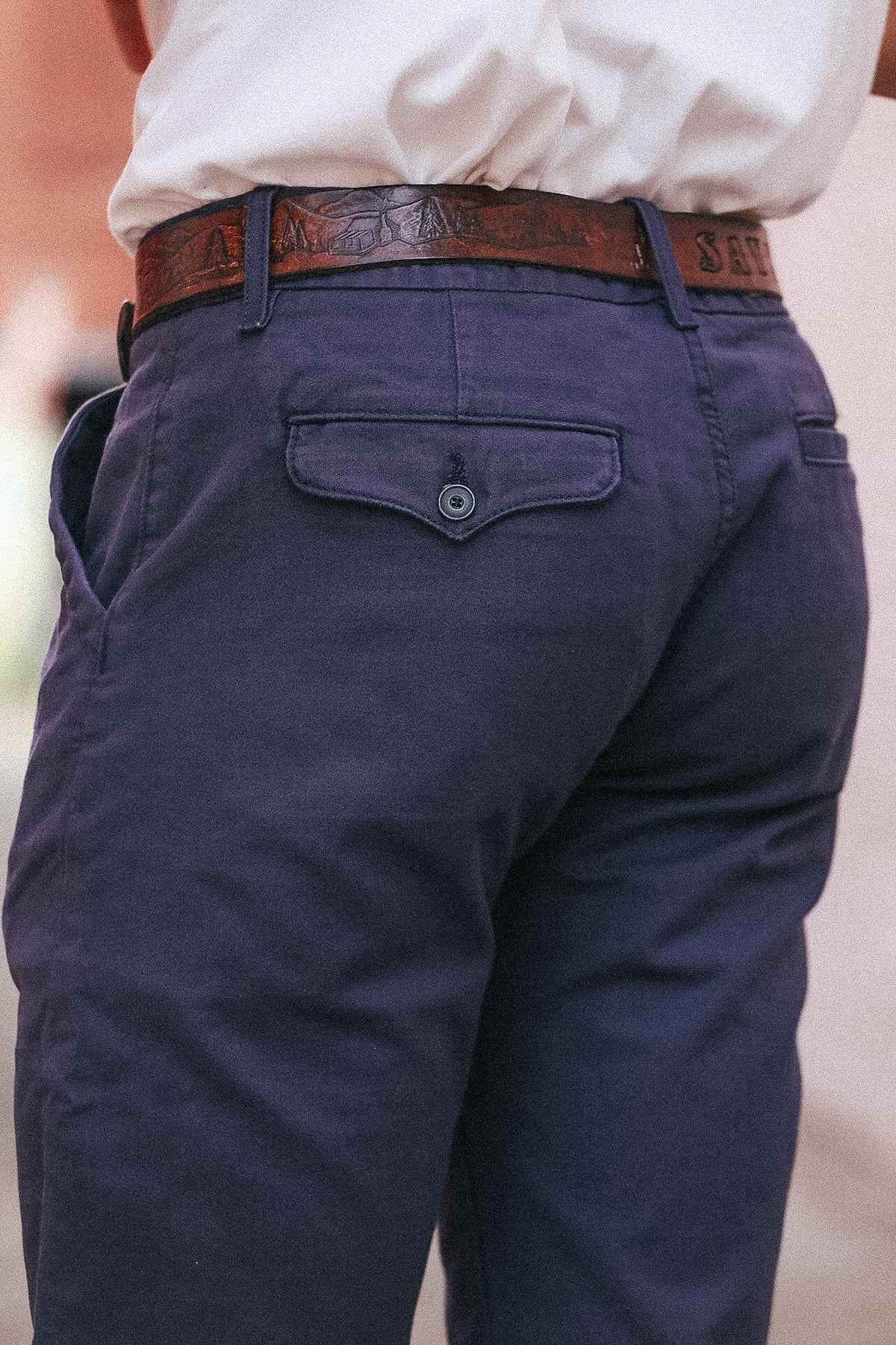 Navy blue pants with a brown belt worn by a person.
