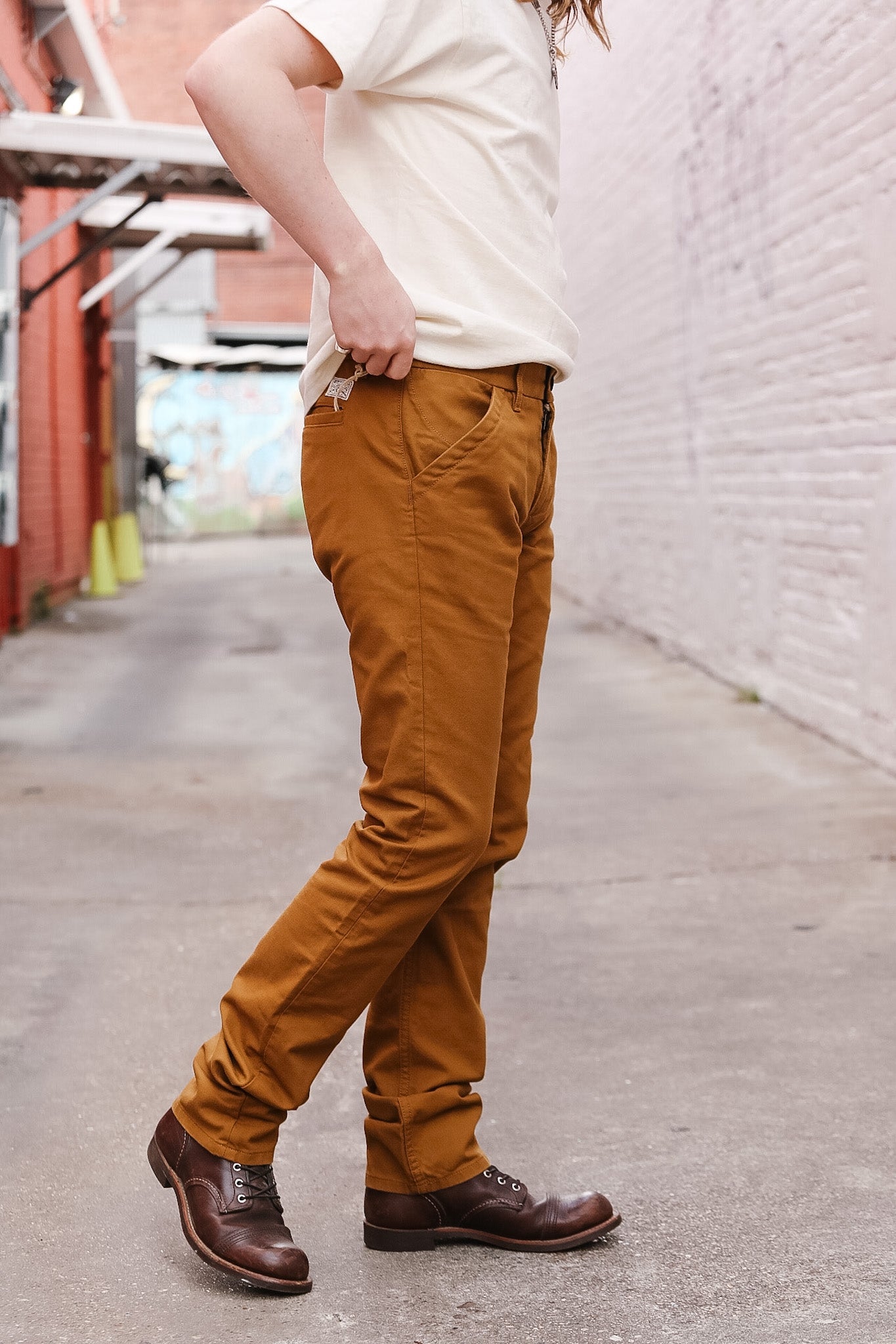 Person wearing mustard yellow pants and brown shoes on a street.