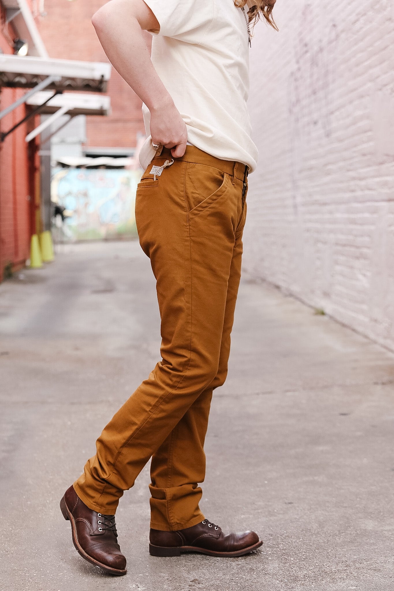 Person wearing mustard yellow pants and brown shoes on a street.