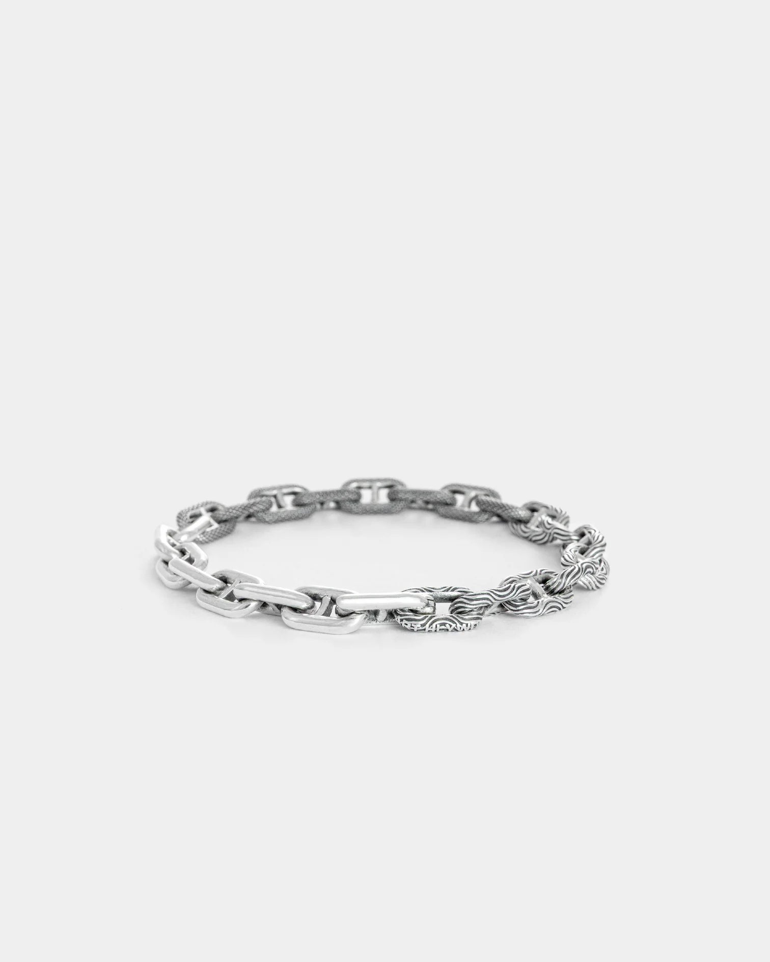 Sterling silver mixed motif bracelet with polished and textured chain links on white background