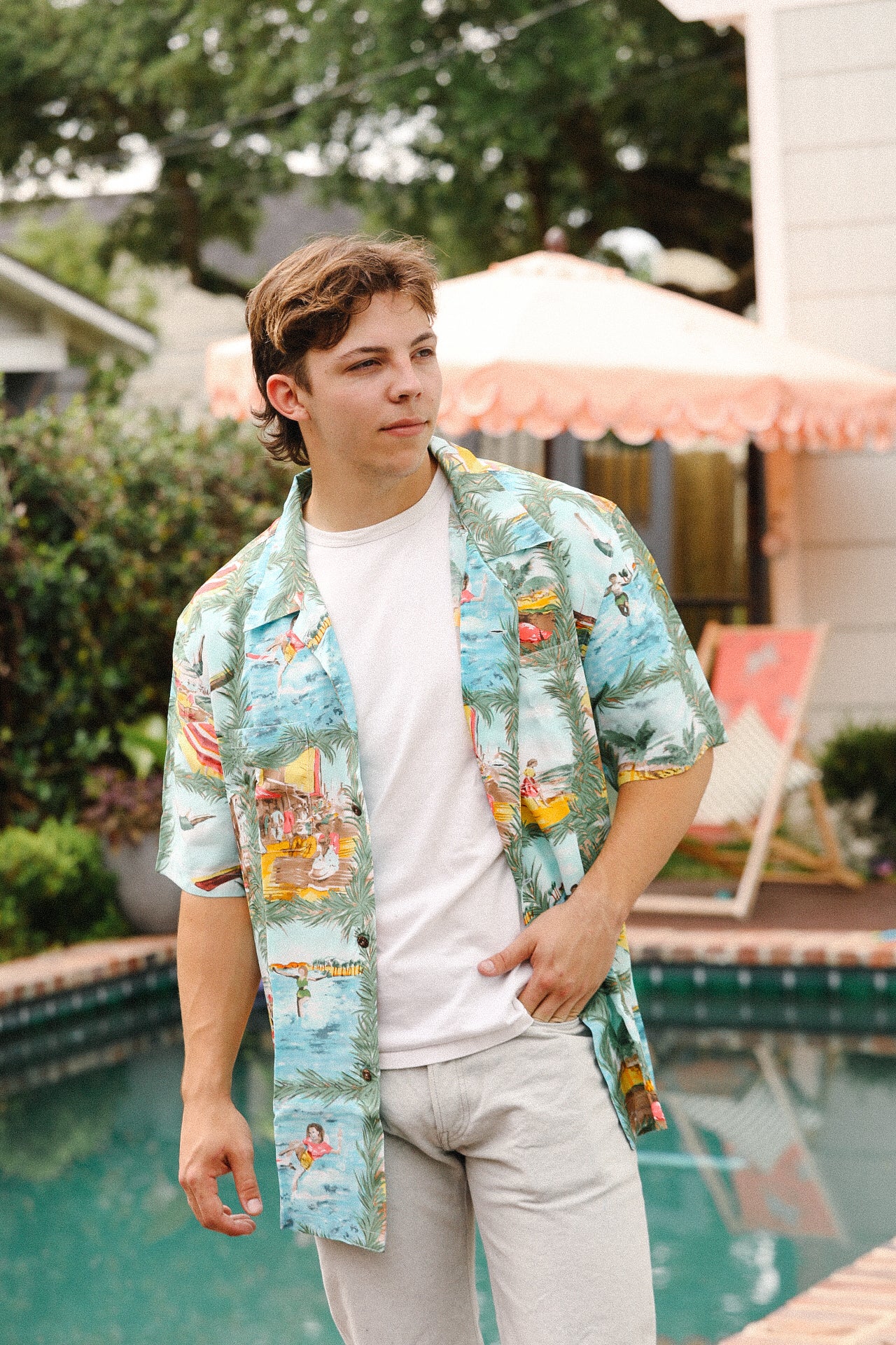 Person wearing a colorful hawaiian shirt by a poolside