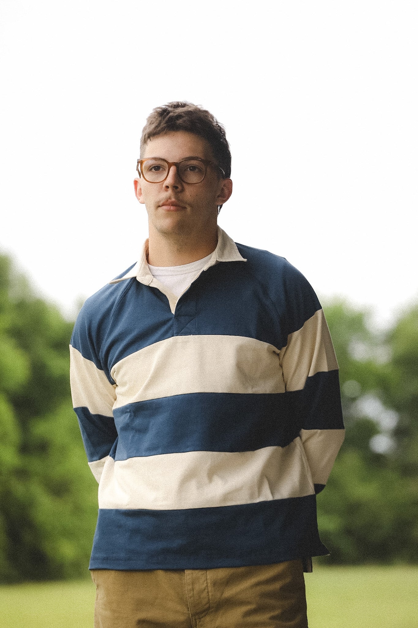 Close-up of a person wearing a blue and beige striped sweater with a blurred background