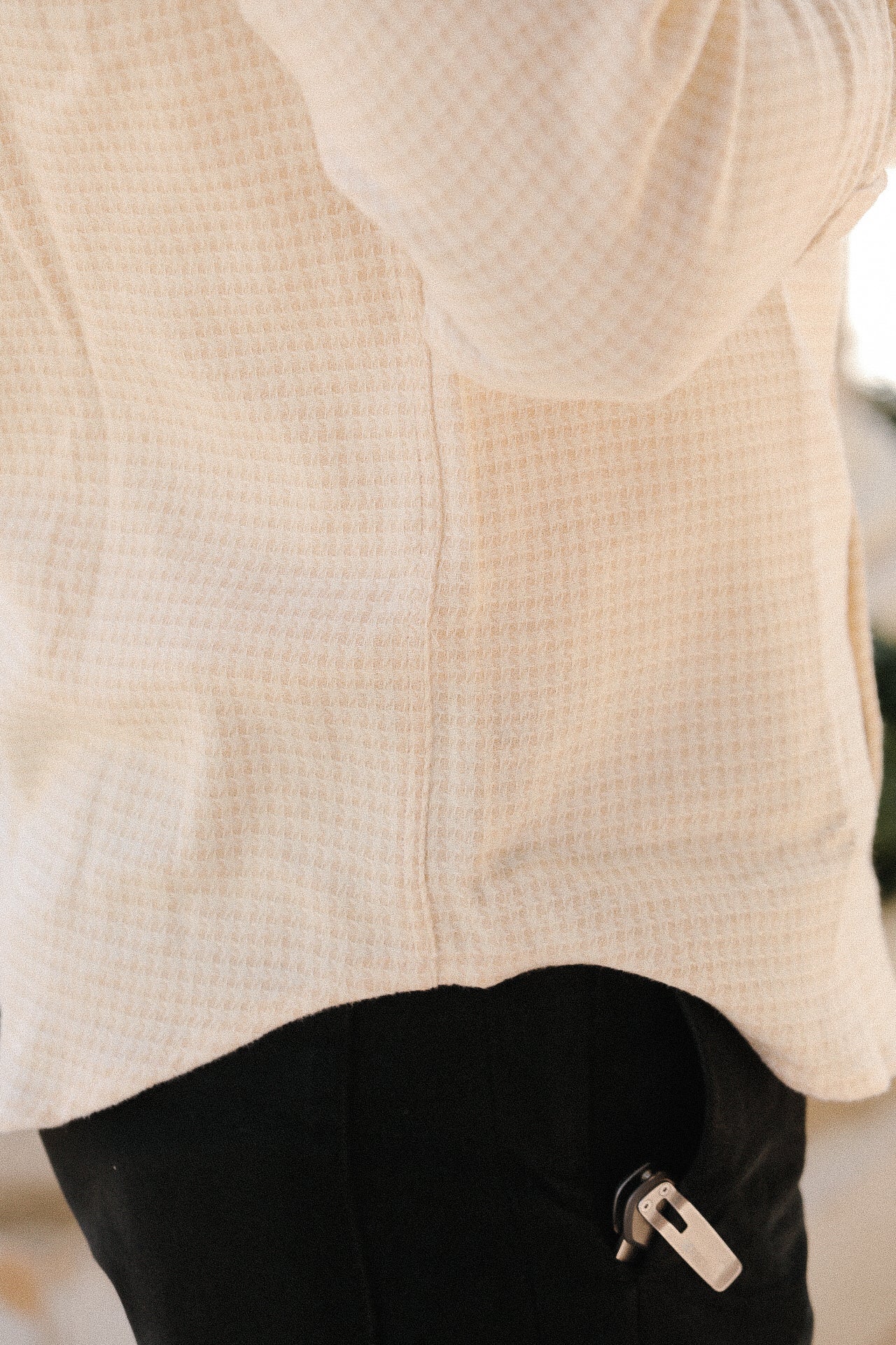 Close-up of cream-colored waffle knit flannel shirt paired with black pants and a metal clip attached.