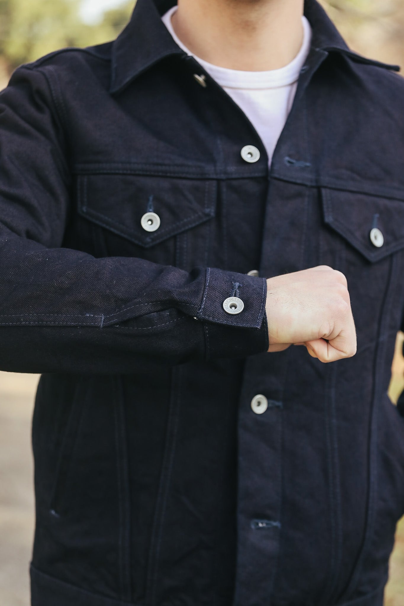 Person wearing a dark jacket with visible buttons, blurred background