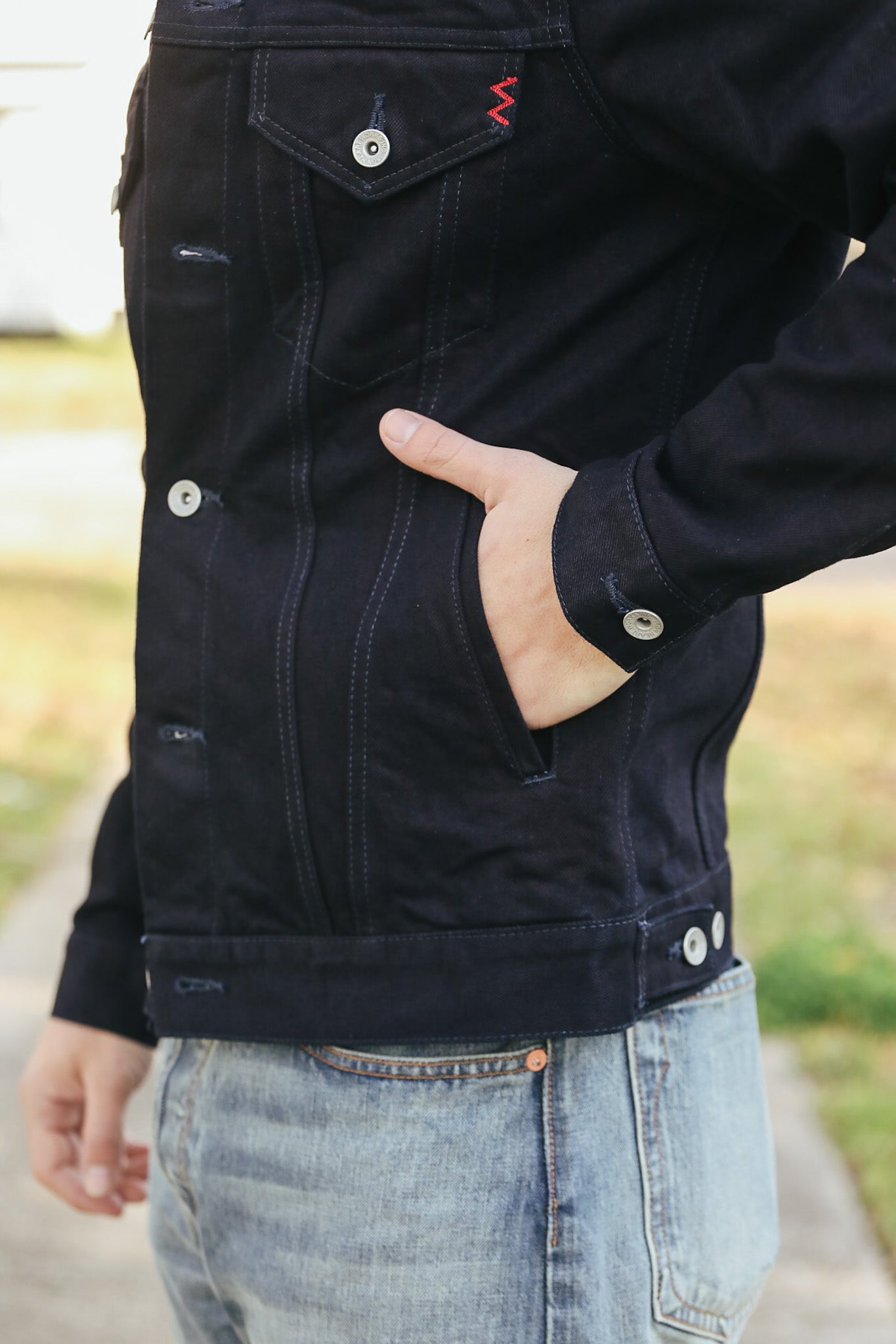 Person wearing a black jacket with visible buttons and a blurred background