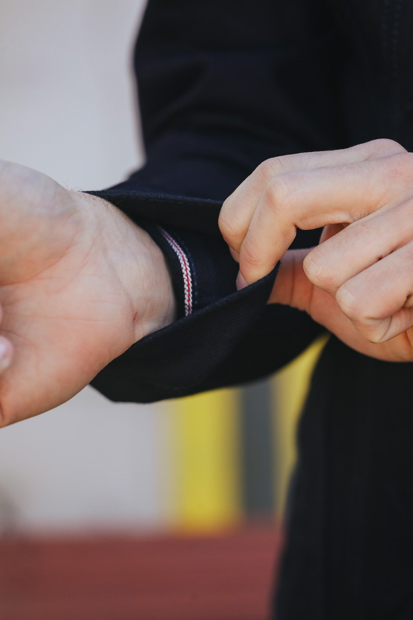 Close-up of hands adjusting a dark jacket sleeve with a blurred background