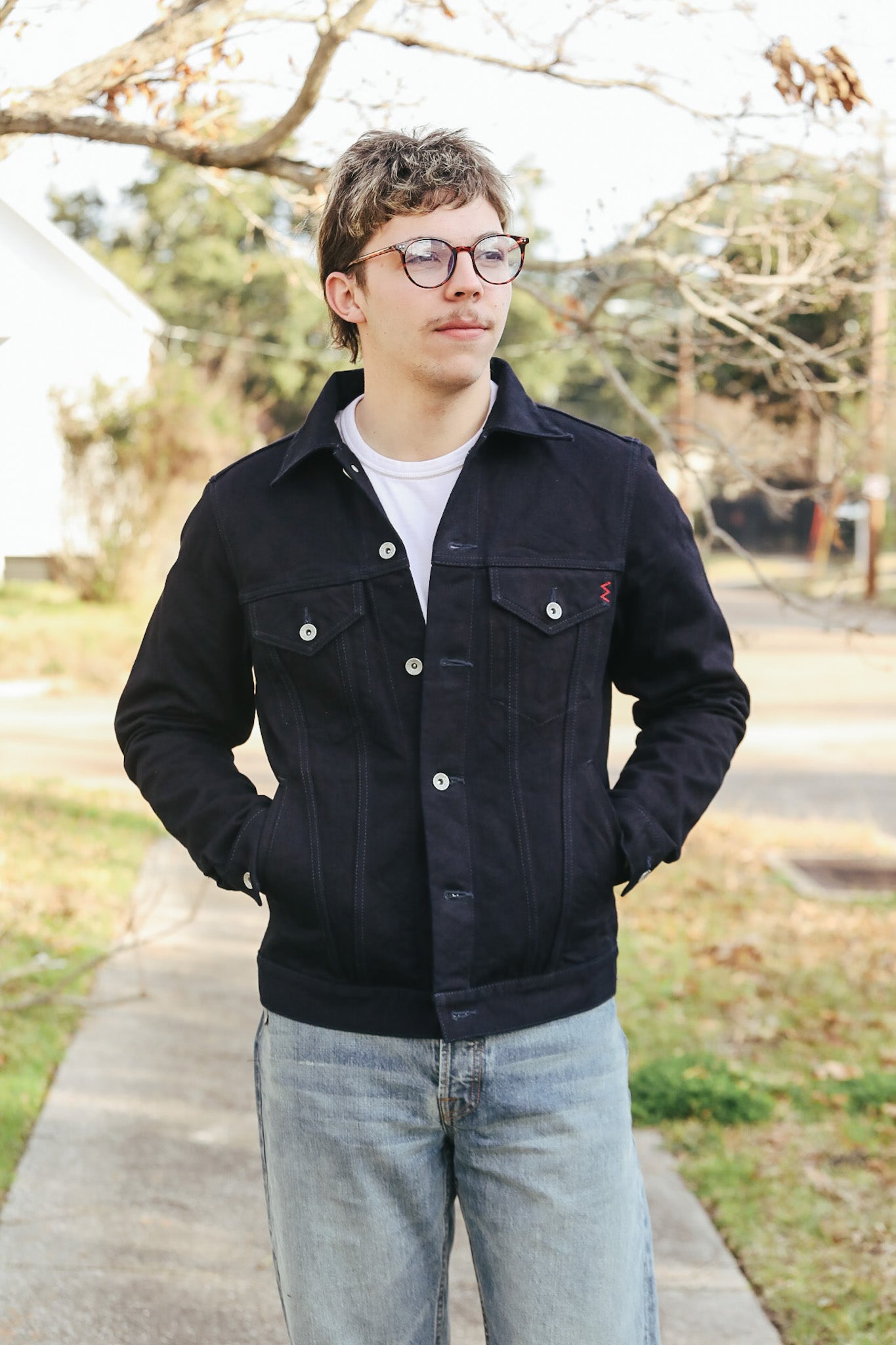 Person wearing a black jacket and glasses outdoors