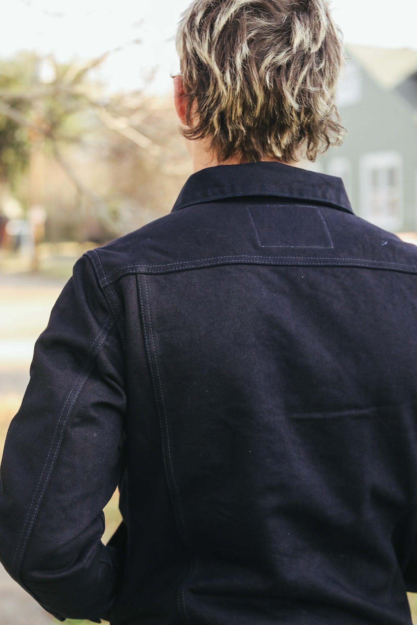 Person wearing a dark jacket with a blurred outdoor background