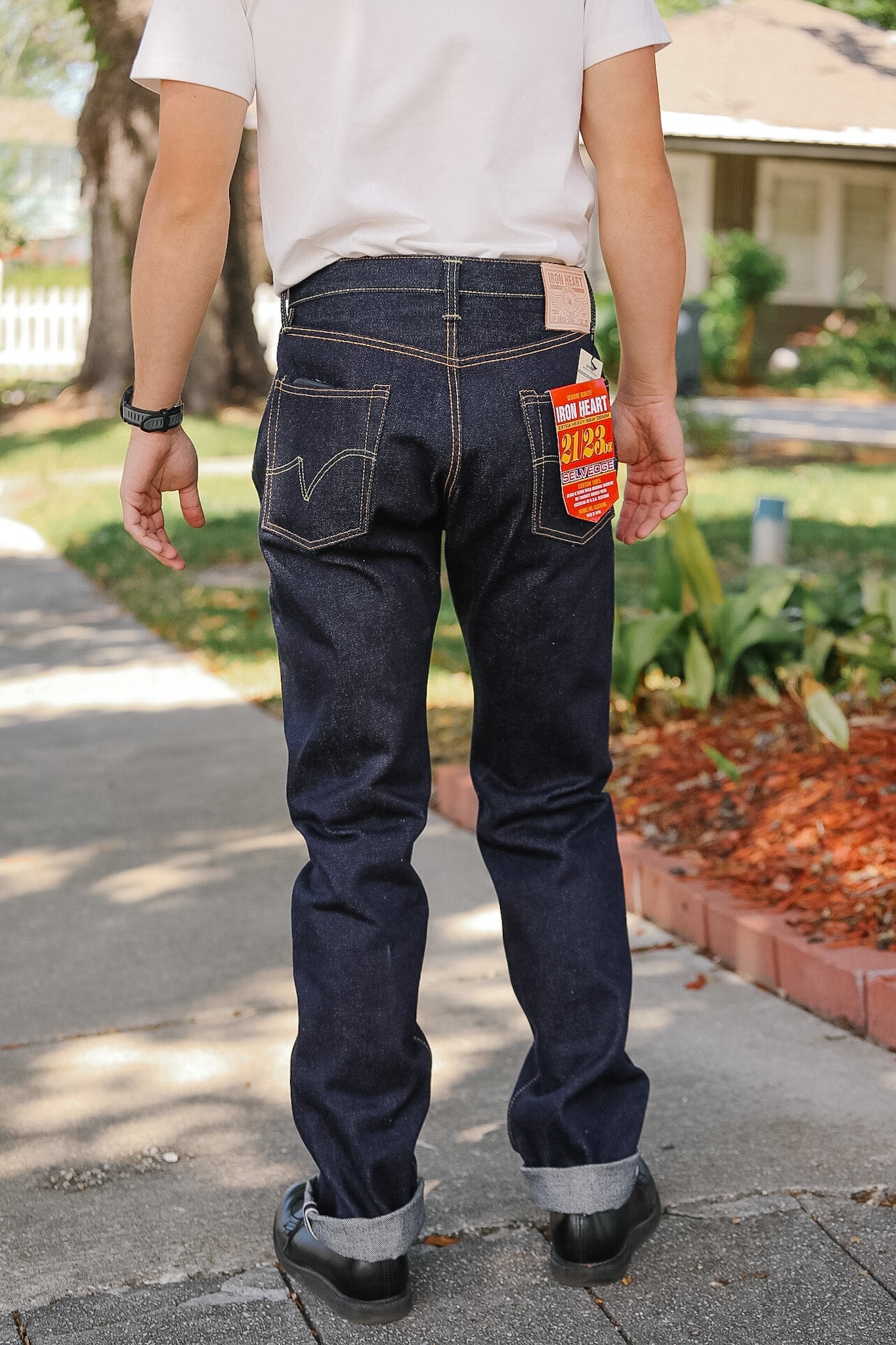 Person wearing dark blue jeans with a visible brand label outdoors.