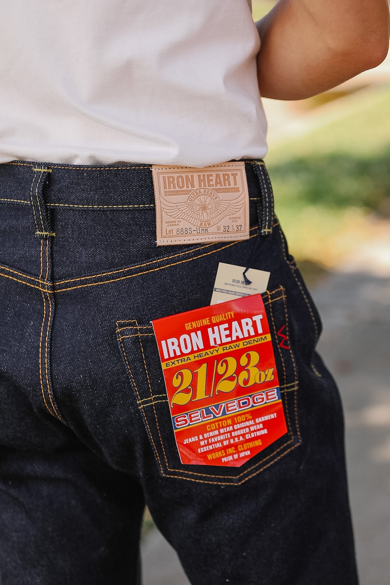 Close-up of dark blue jeans with 'Iron Heart' label on pocket and back waistband.