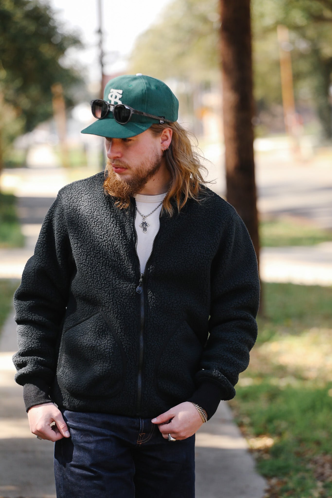 Man wearing a black jacket and green cap outdoors