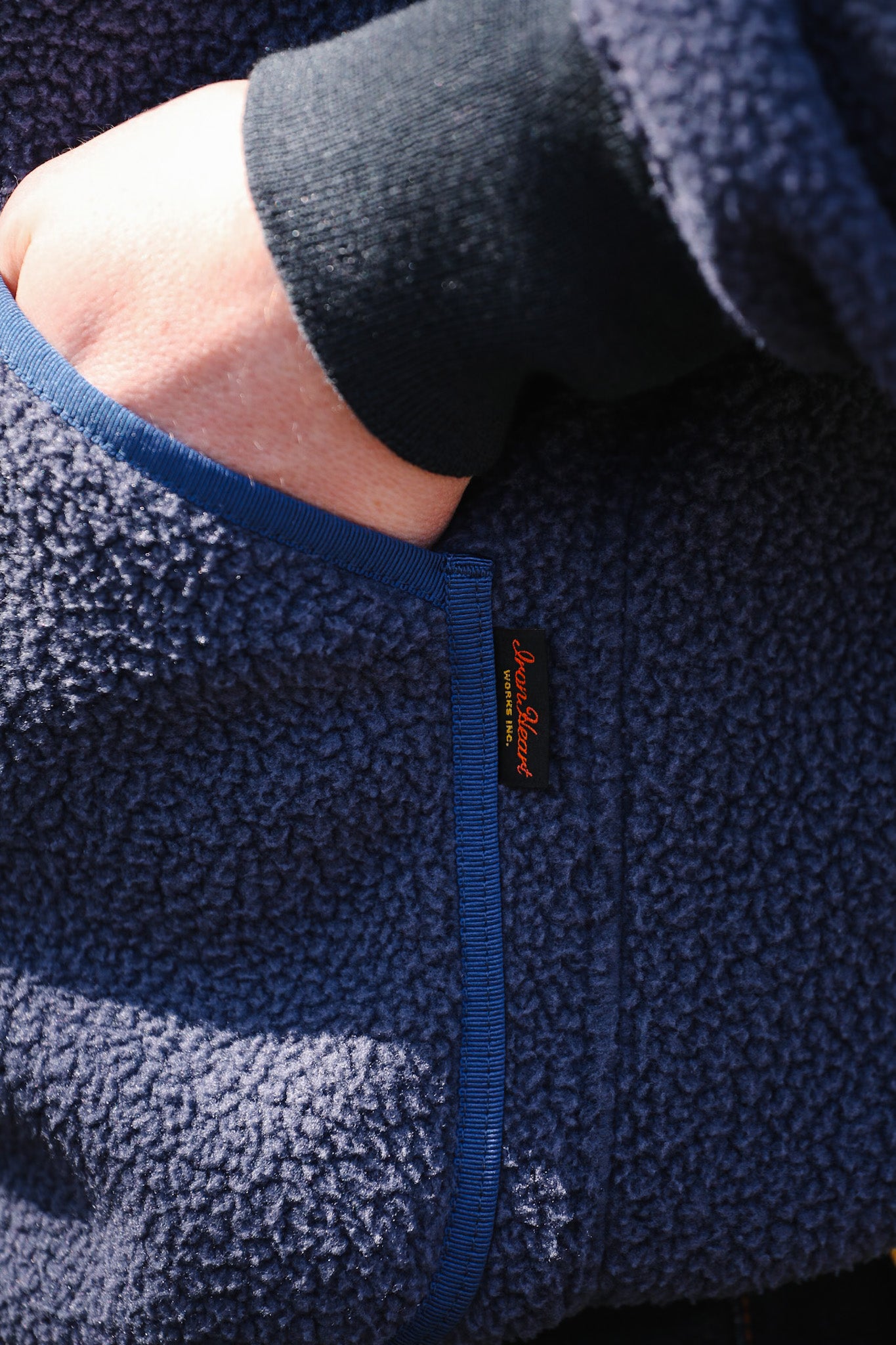 Close-up of a navy fleece jacket with a brand logo on the chest.