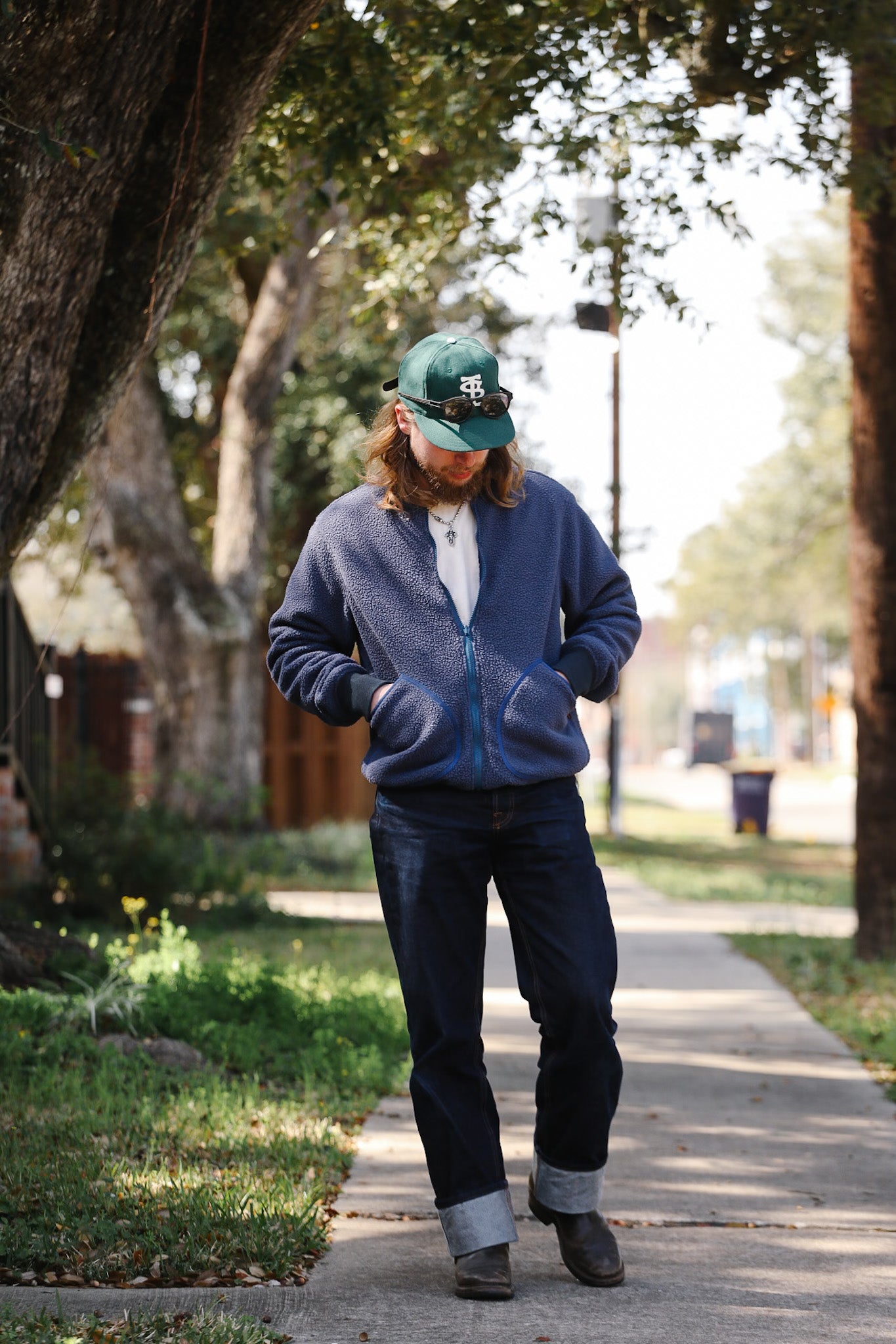 Person walking on a sidewalk with trees and a building in the background