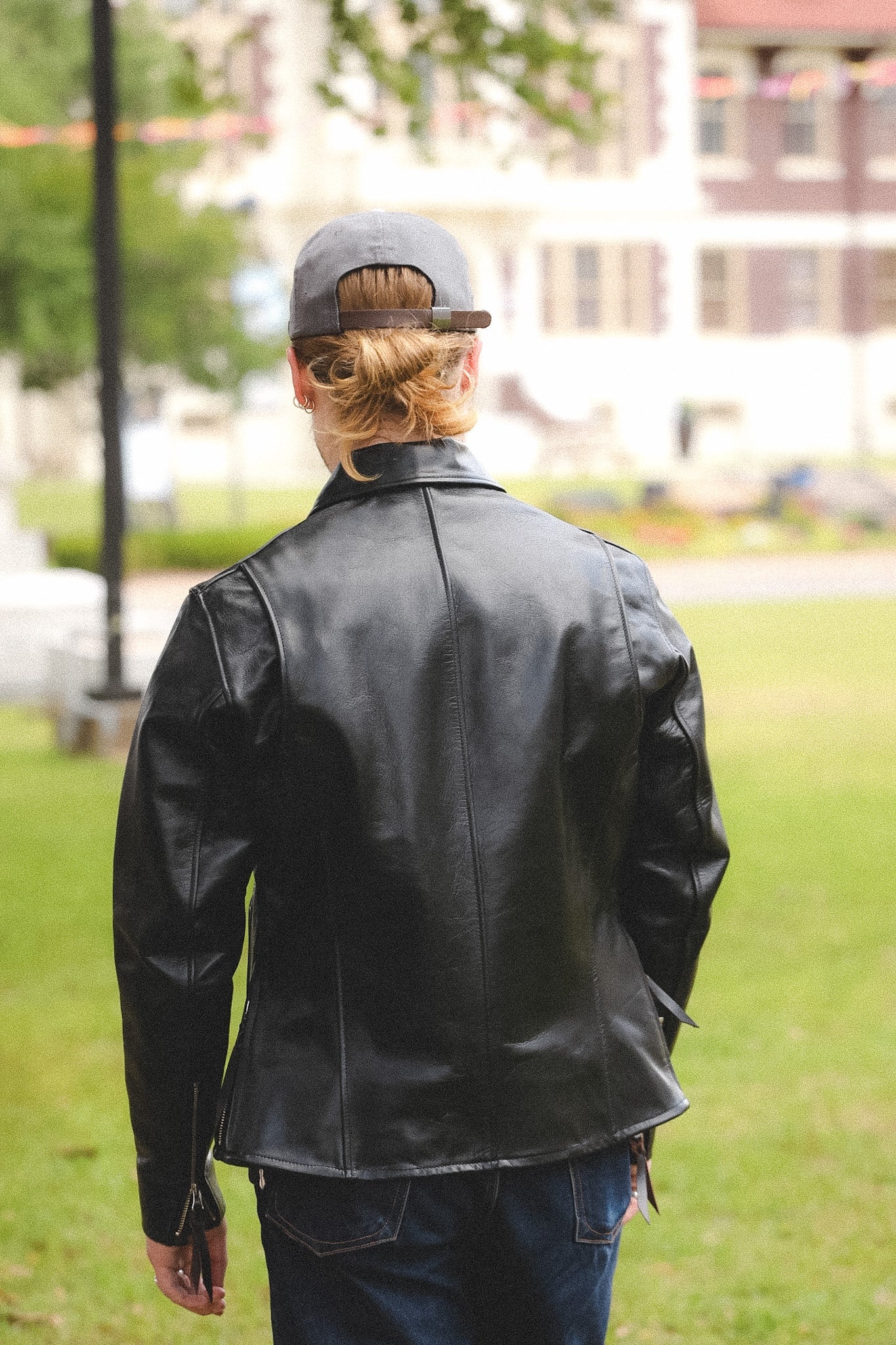 A person wearing a black horsehide rider's jacket with a collar, standing outdoors.