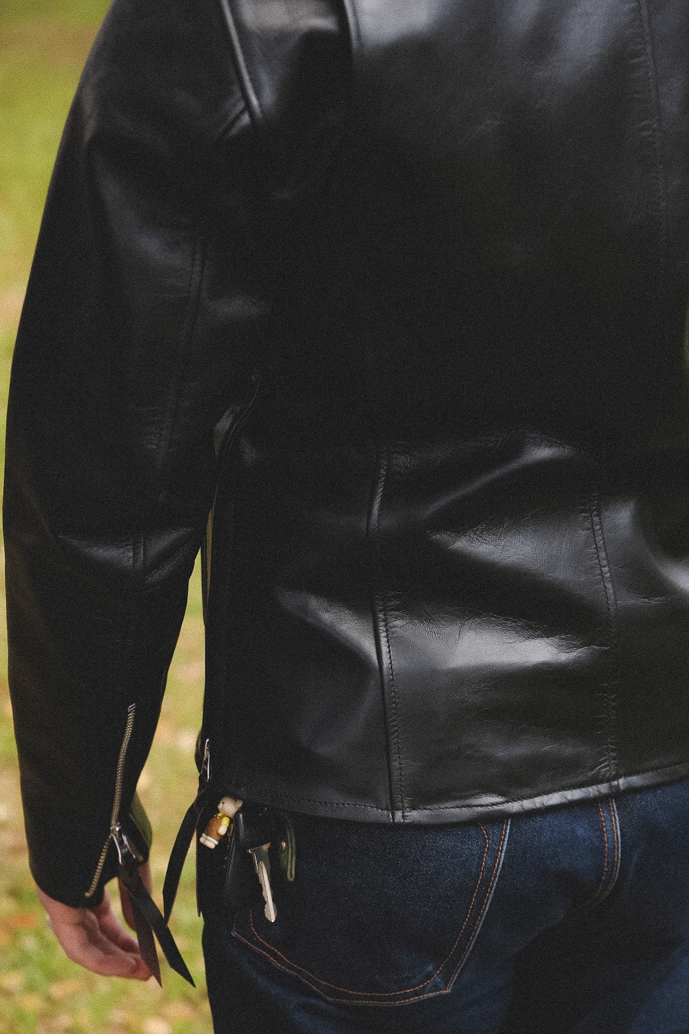 A person wearing a black horsehide rider's jacket with a collar, standing outdoors.
