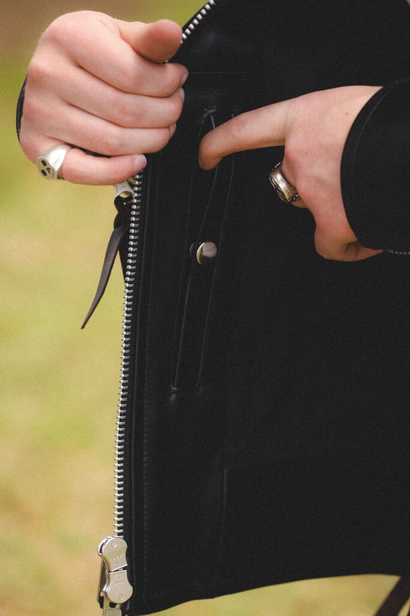 A person wearing a black horsehide rider's jacket with a collar, standing outdoors.