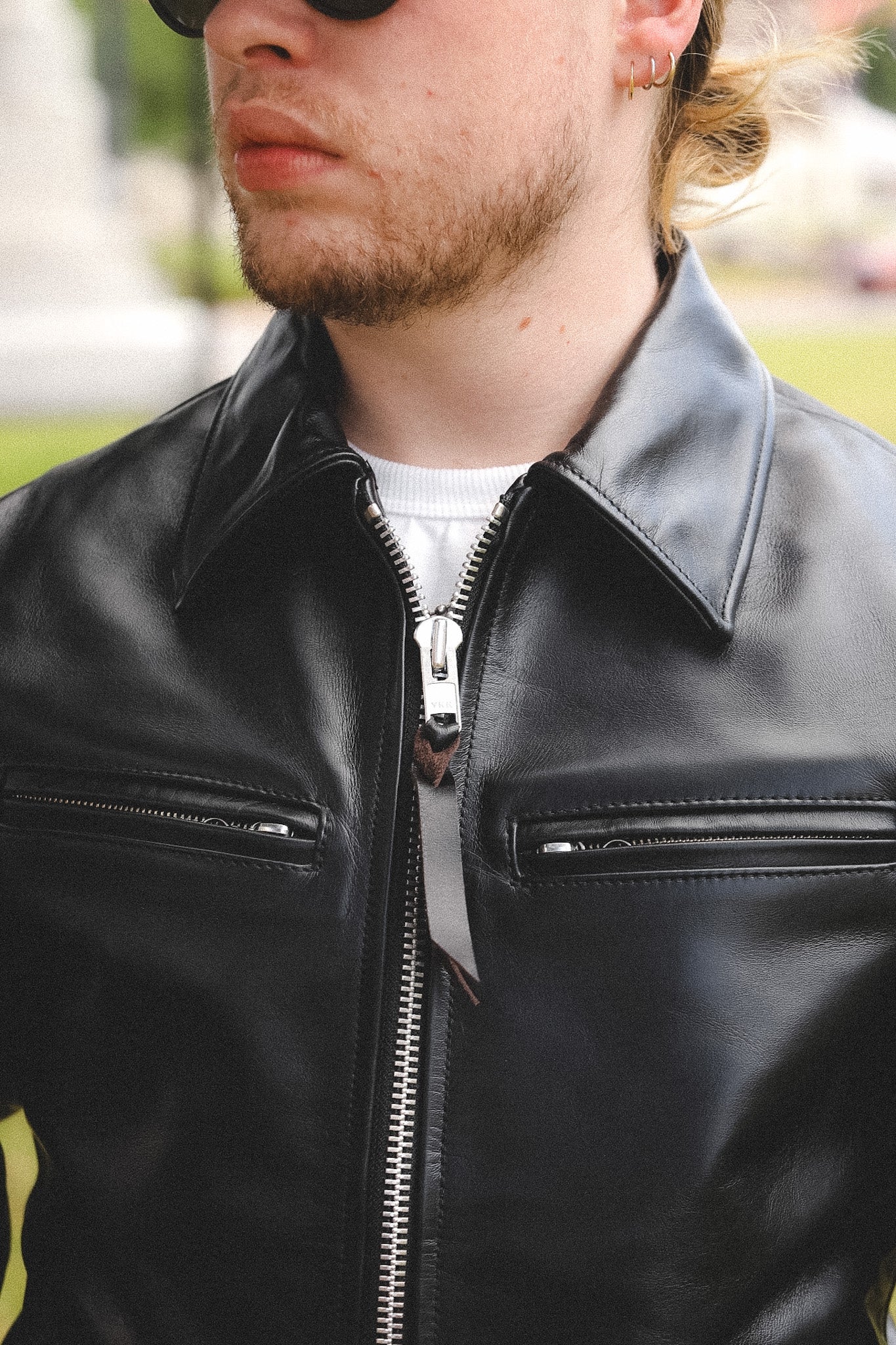 A person wearing a black horsehide rider's jacket with a collar, standing outdoors.