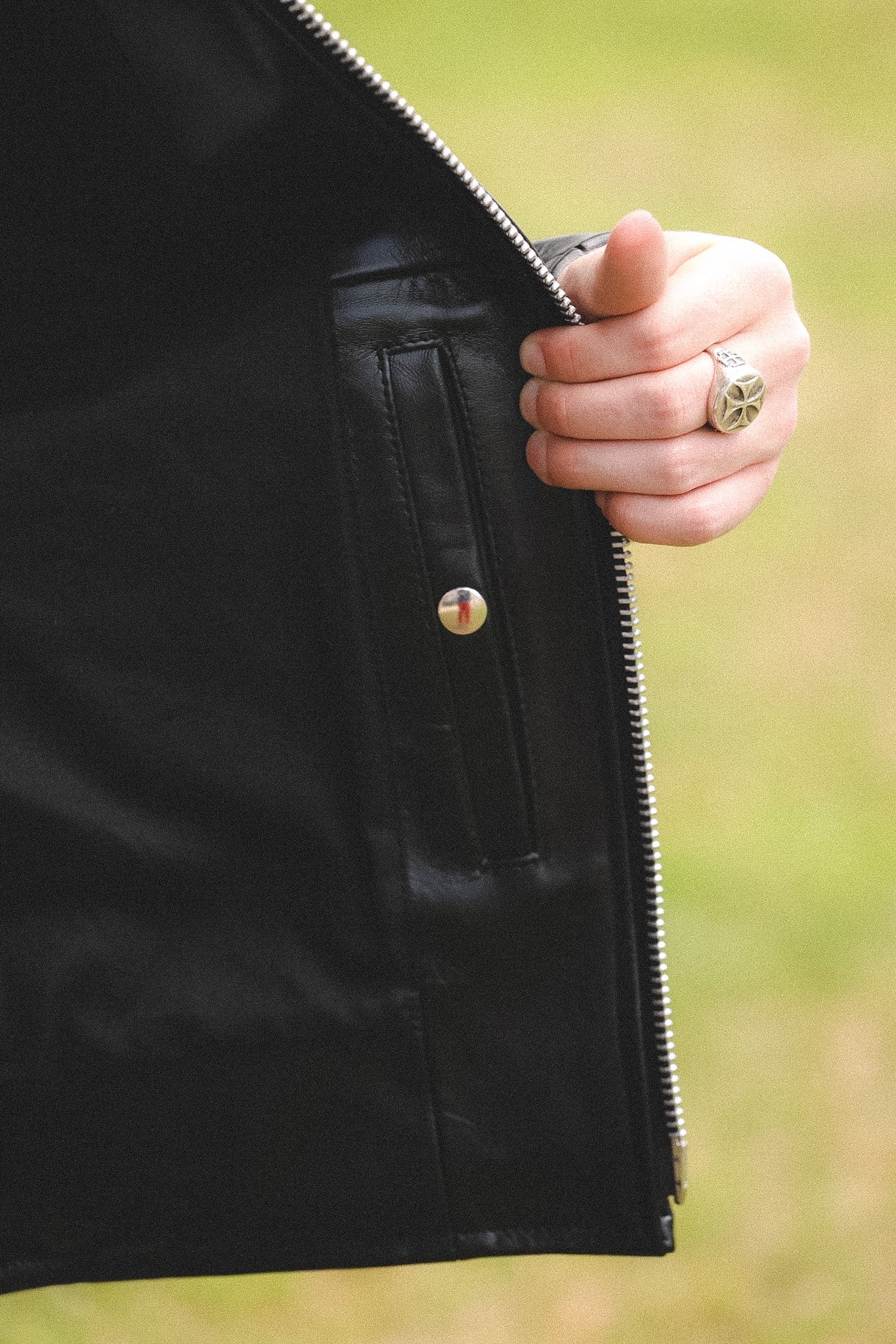 A person wearing a black horsehide rider's jacket with a collar, standing outdoors