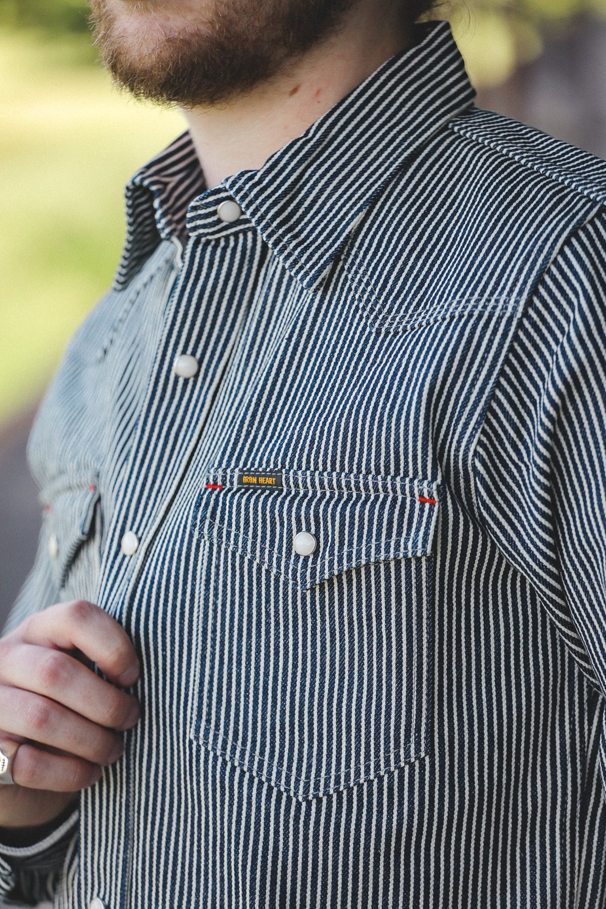 Close-up of a man wearing a blue and white vertically striped button-down shirt with a chest pocket and white buttons.