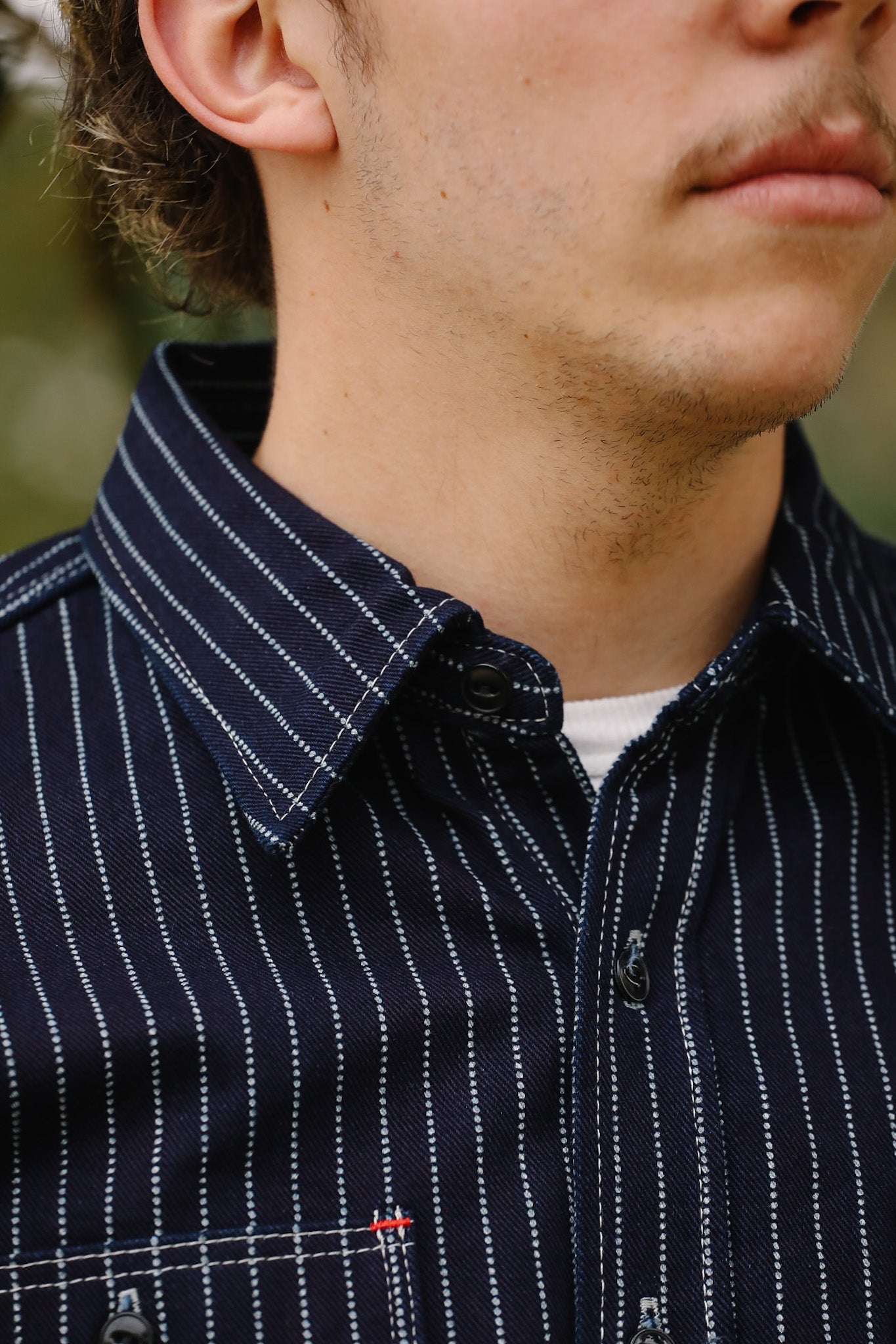 Close-up of a person wearing a dark blue shirt with white stripes.