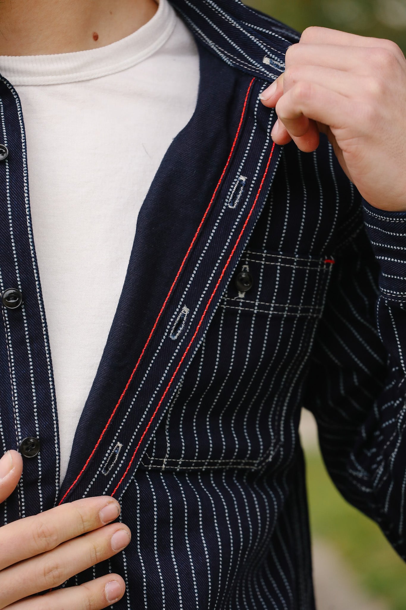 Navy pinstripe suit jacket with white shirt and blurred background