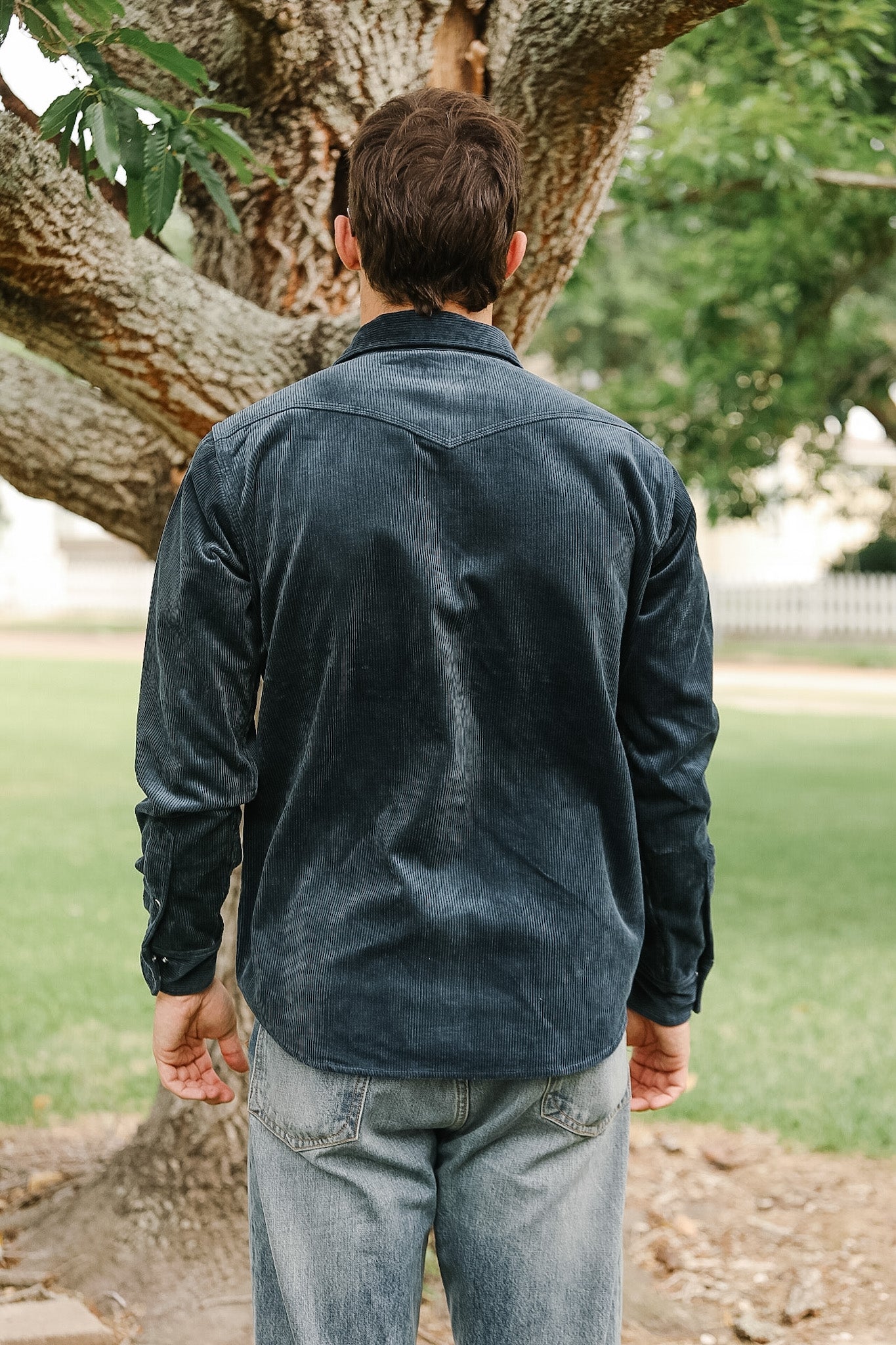 Close-up of a hand buttoning a dark blue corduroy jacket.