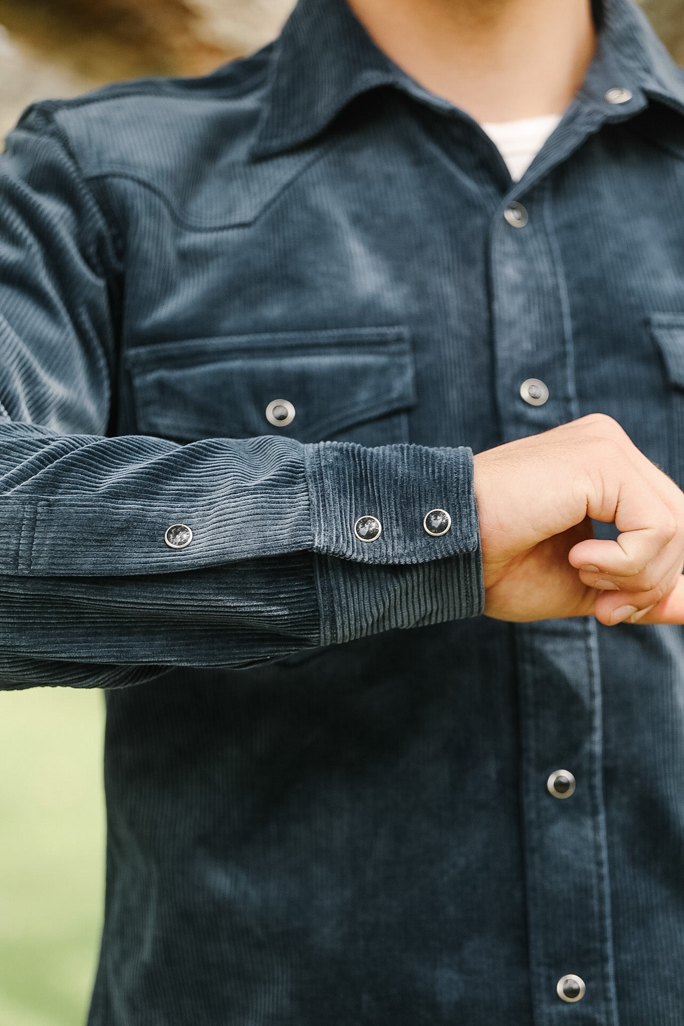 Close-up of a person wearing a dark blue corduroy shirt with buttons.