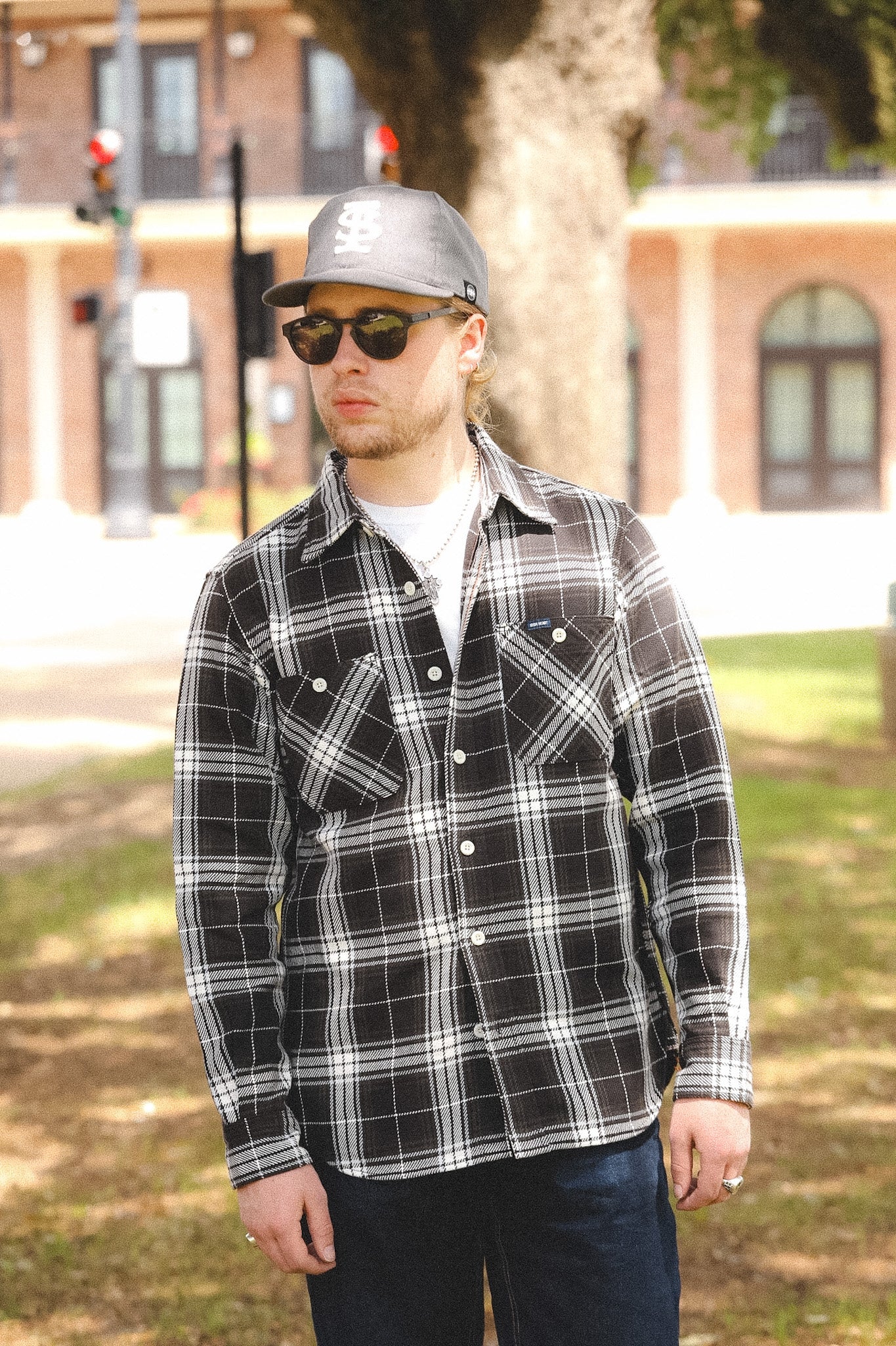 man wearing plaid black shirt standing outdoors on a blurred background 