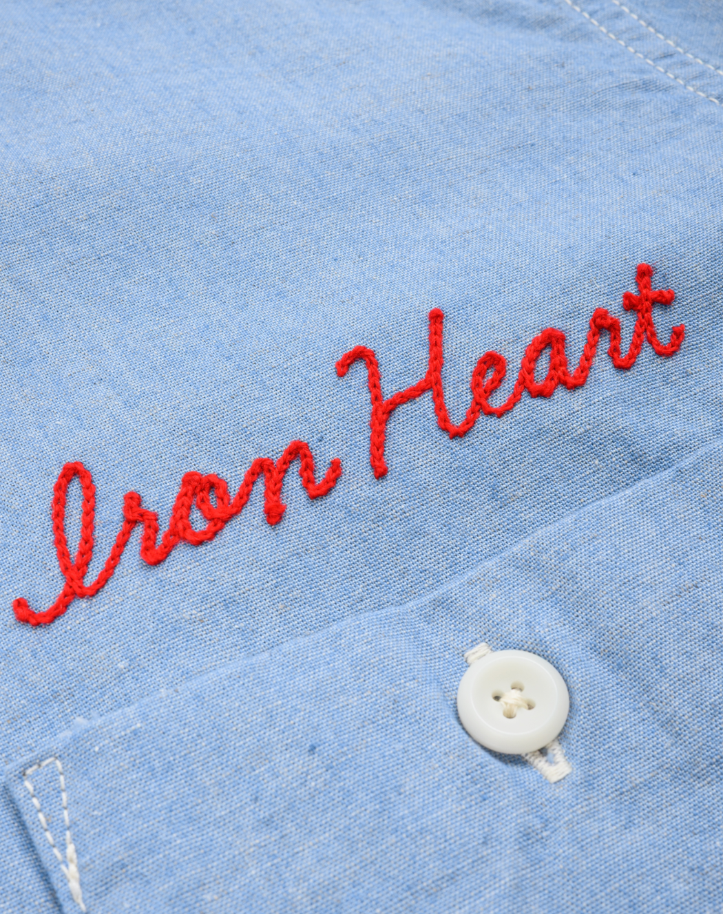 Blue denim jacket with 'Iron Heart' embroidery and a white button.