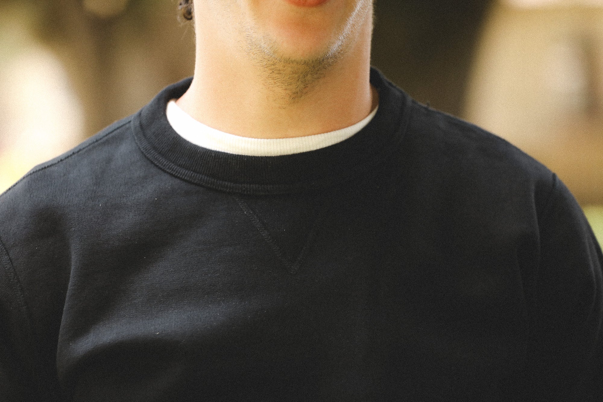 Close-up of a person wearing a black sweatshirt with a blurred background