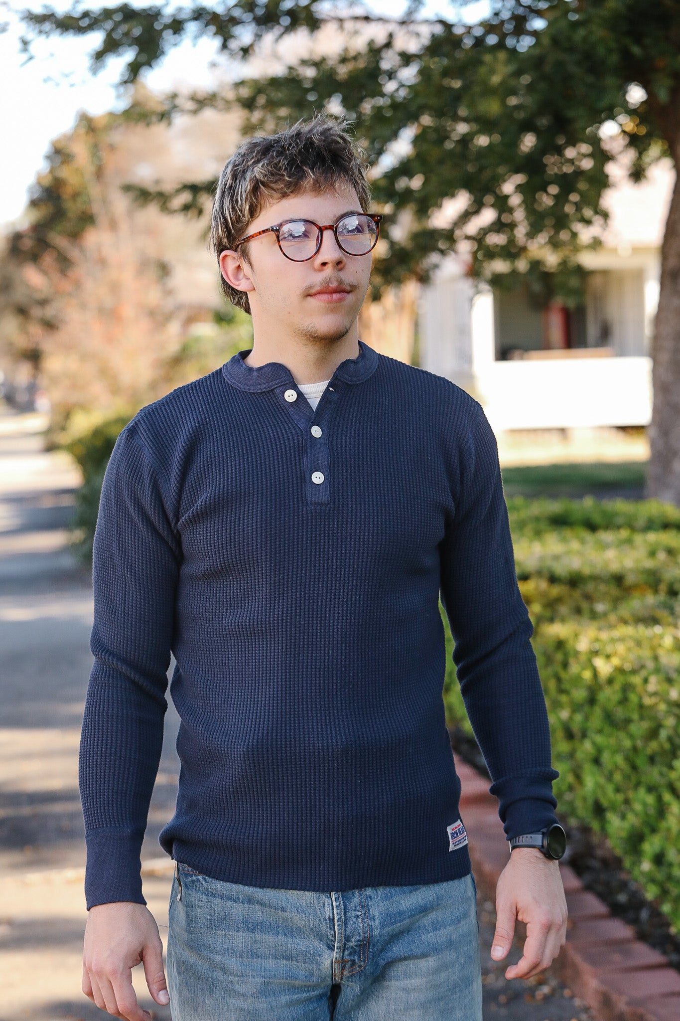 Person wearing a navy long-sleeve shirt with white buttons outdoors