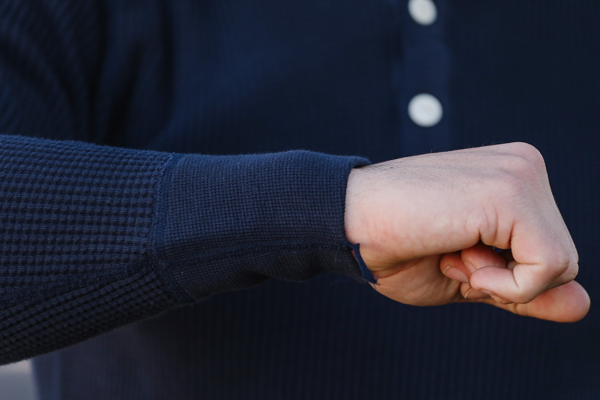 Close-up of a person wearing a dark blue sweater with a buttoned collar.
