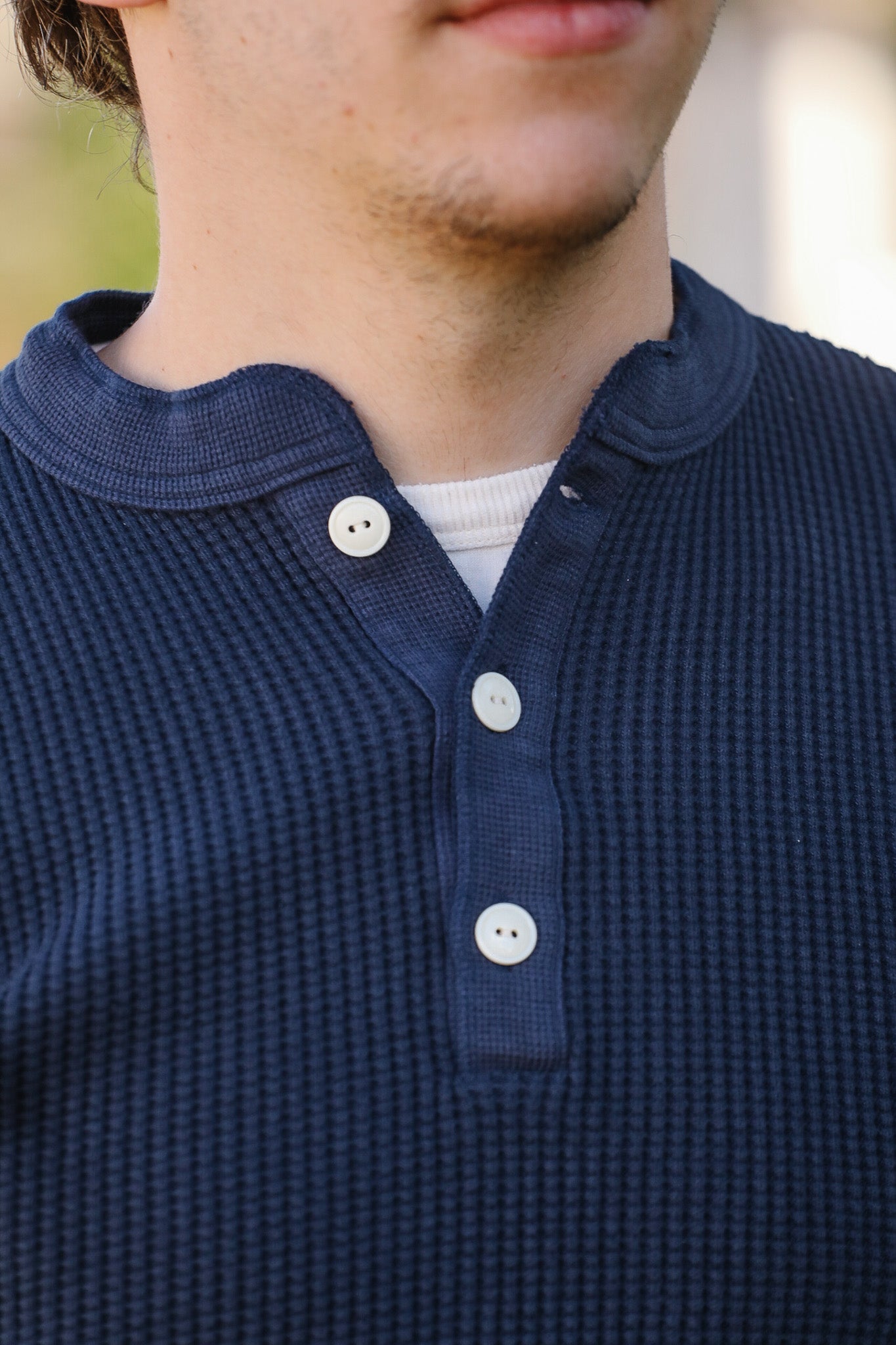 Close-up of a person wearing a blue textured shirt with white buttons.