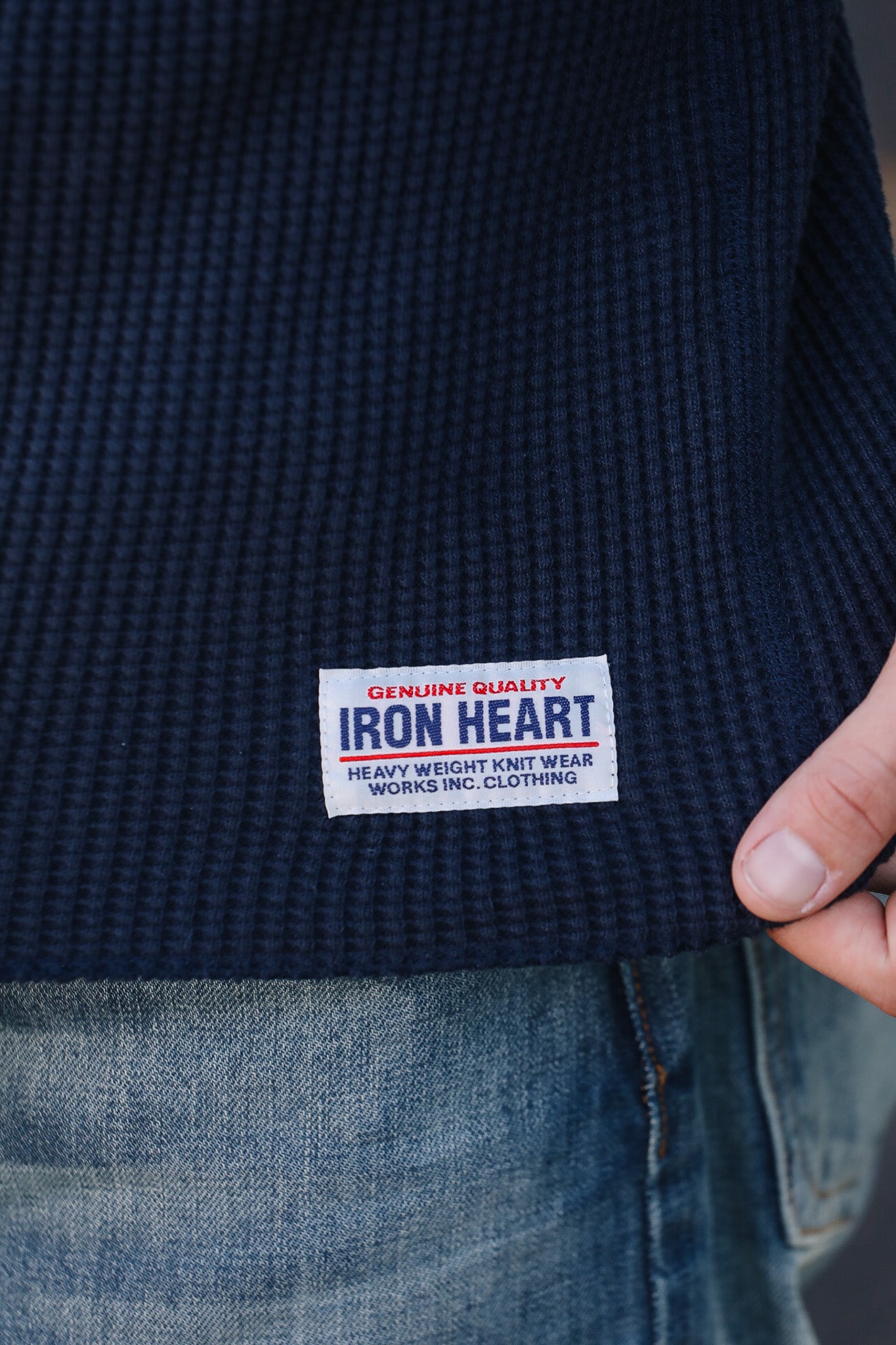 Navy blue garment with Iron Heart label held by a hand