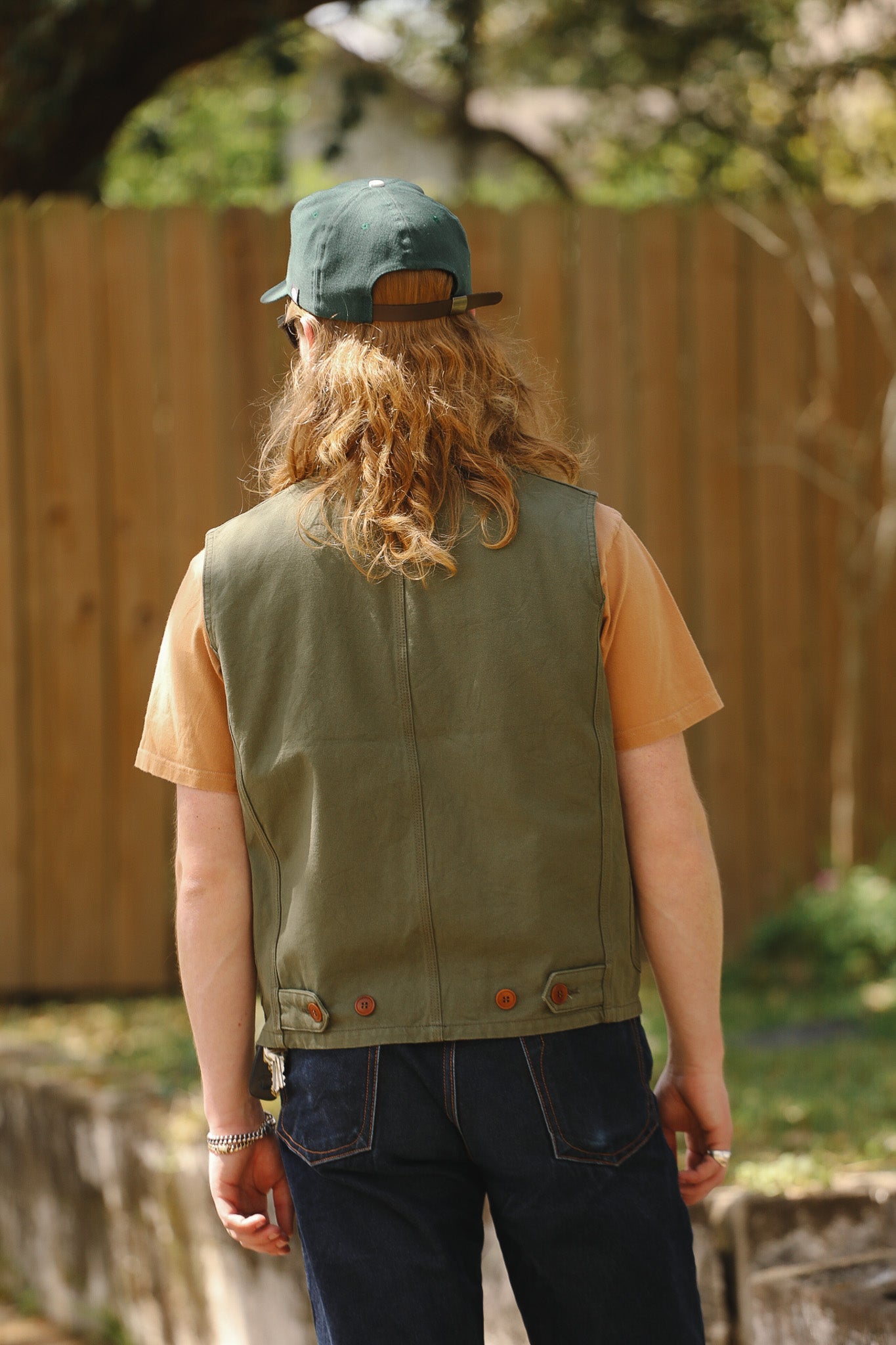 Person wearing a green vest and cap with a blurred background