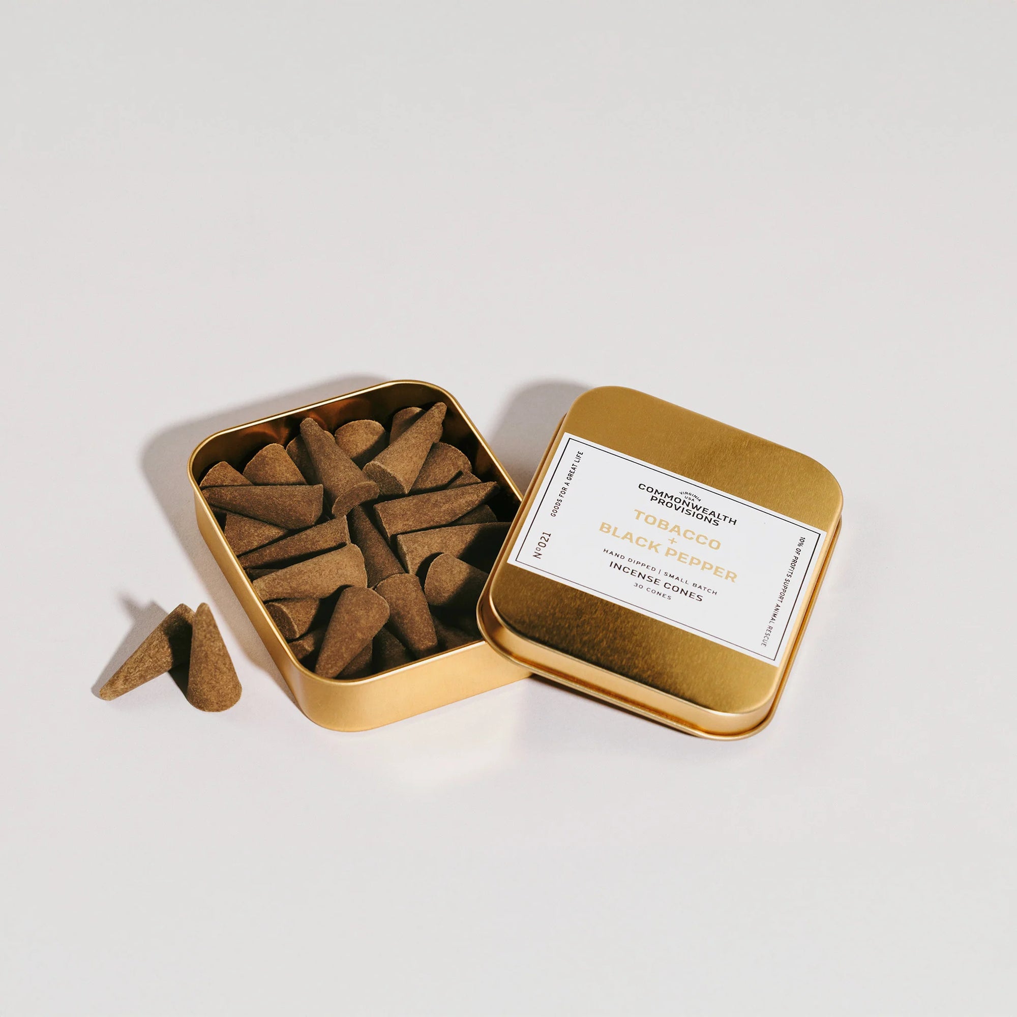 Gold tin of tobacco and black pepper incense cones with open lid showing brown conical incense